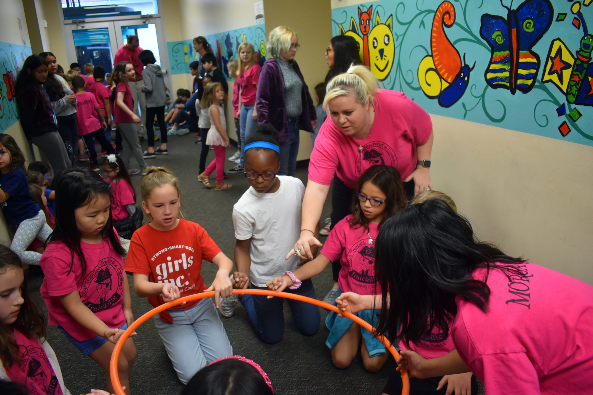 Third grade teacher Kim Forchetti shows students Sophia Tran, Corrine Dubois, Bri'anah Tate and Valentina Monroy how to hold their finger to lift the hula hoop.