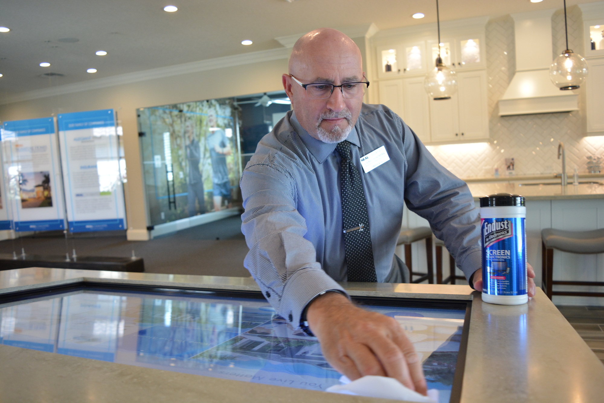 Neal Communities sales associate Craig Forsman disinfects the interactive display he uses to show customers the Indigo community in Lakewood Ranch. Associates are cleaning more to ensure the health of themselves and customers.