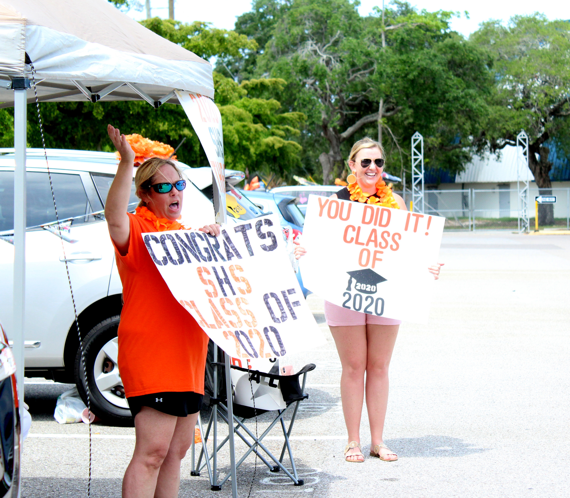 Sue Graham and Alana Hodge greet students as they pull into the parking lot at Sarasota High School.