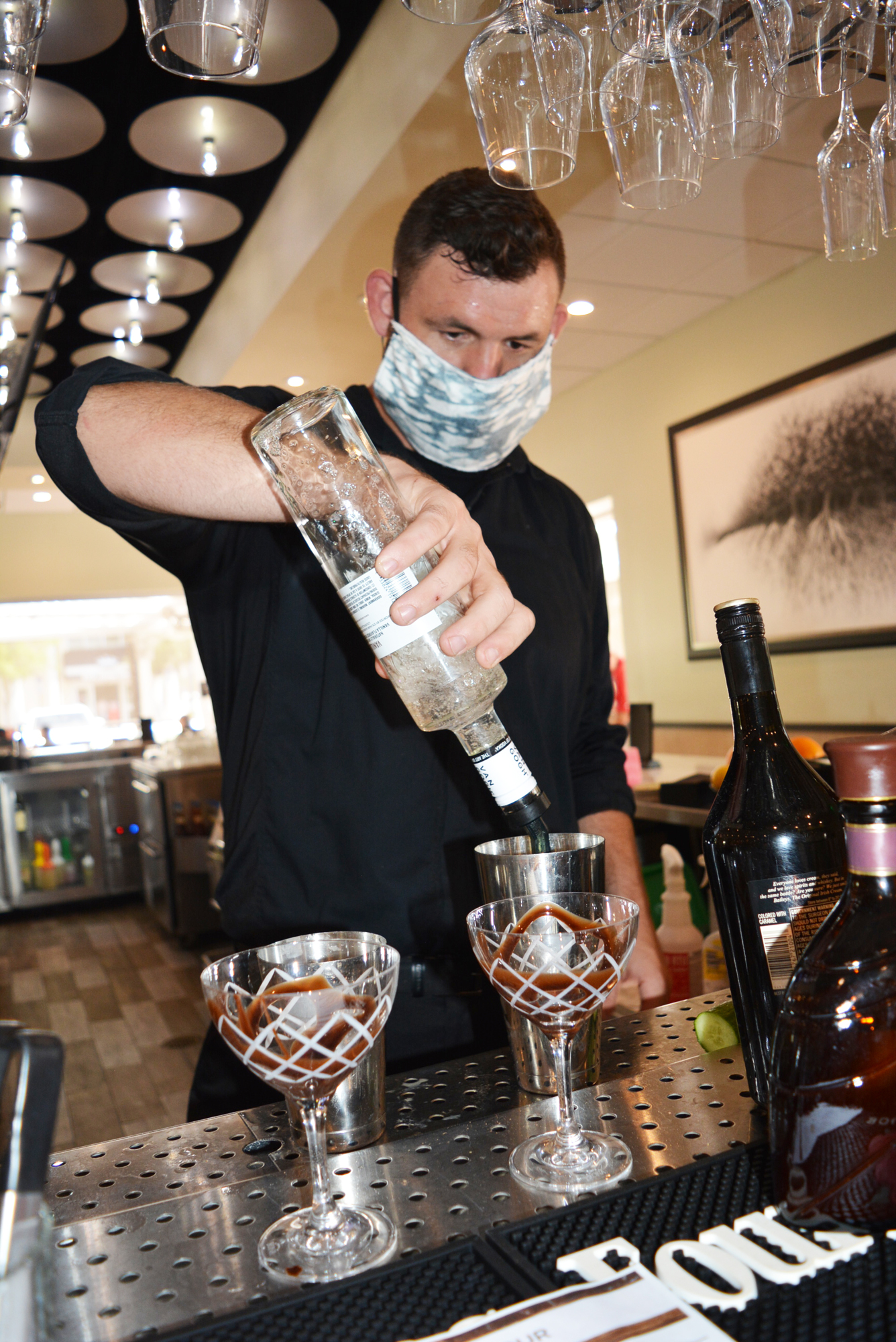 Grove restaurant bartender Mark Nordhausen wears a face mask as he prepares two chocolate martinis for customers.