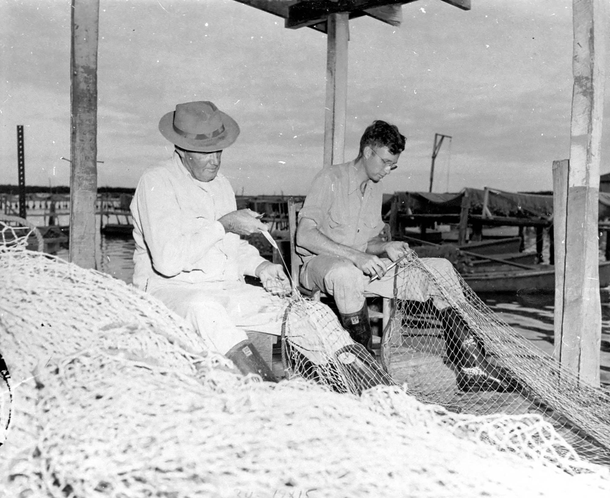 Walt (Tink) and Ralph Fulford mending fish nets in Cortez, circa 1954.