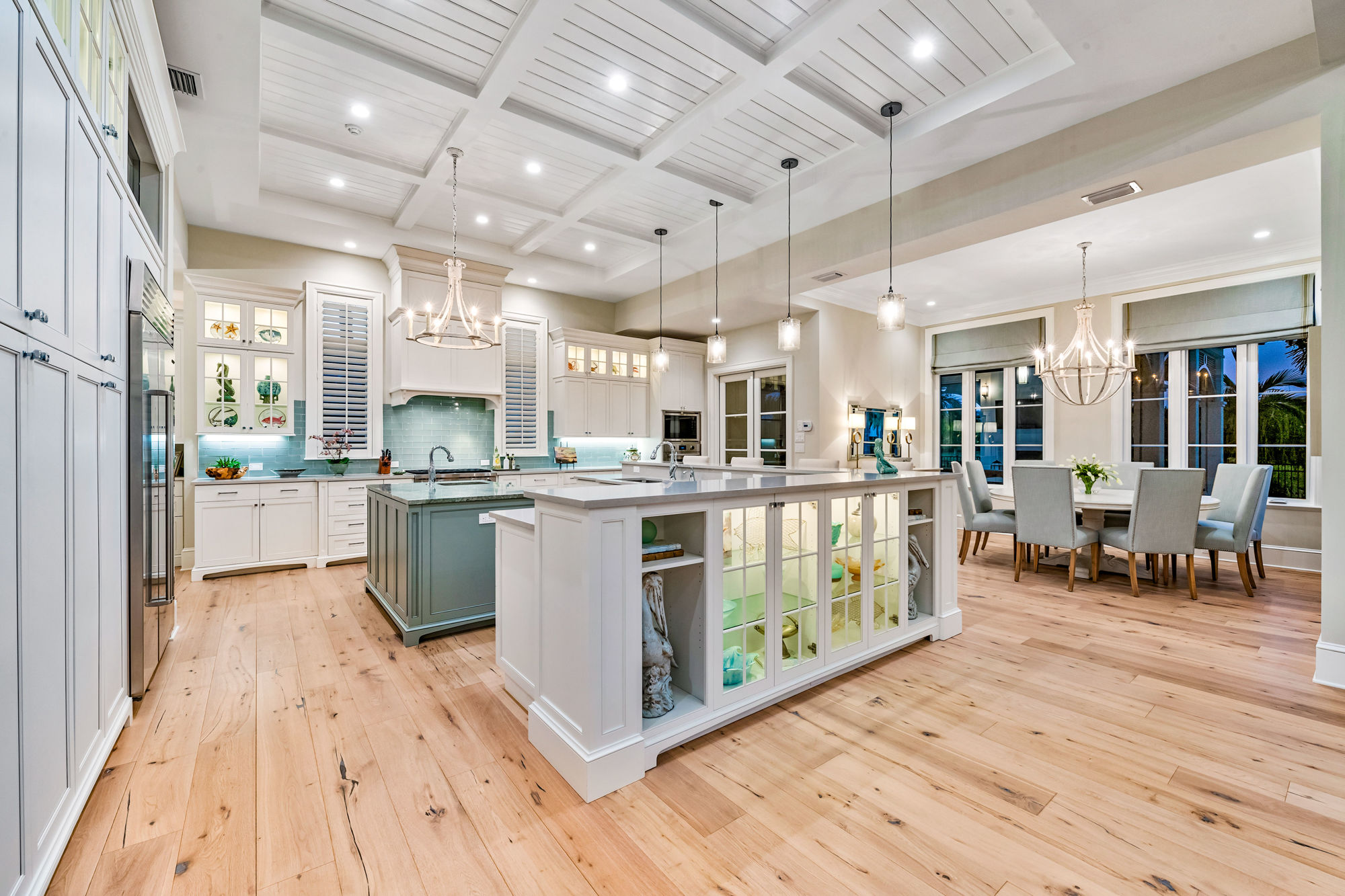 Cabinetry and kitchen islands were built to resemble furniture. A round dining table overlooks the pool, and to the left, a wall of built-ins provides extra storage.