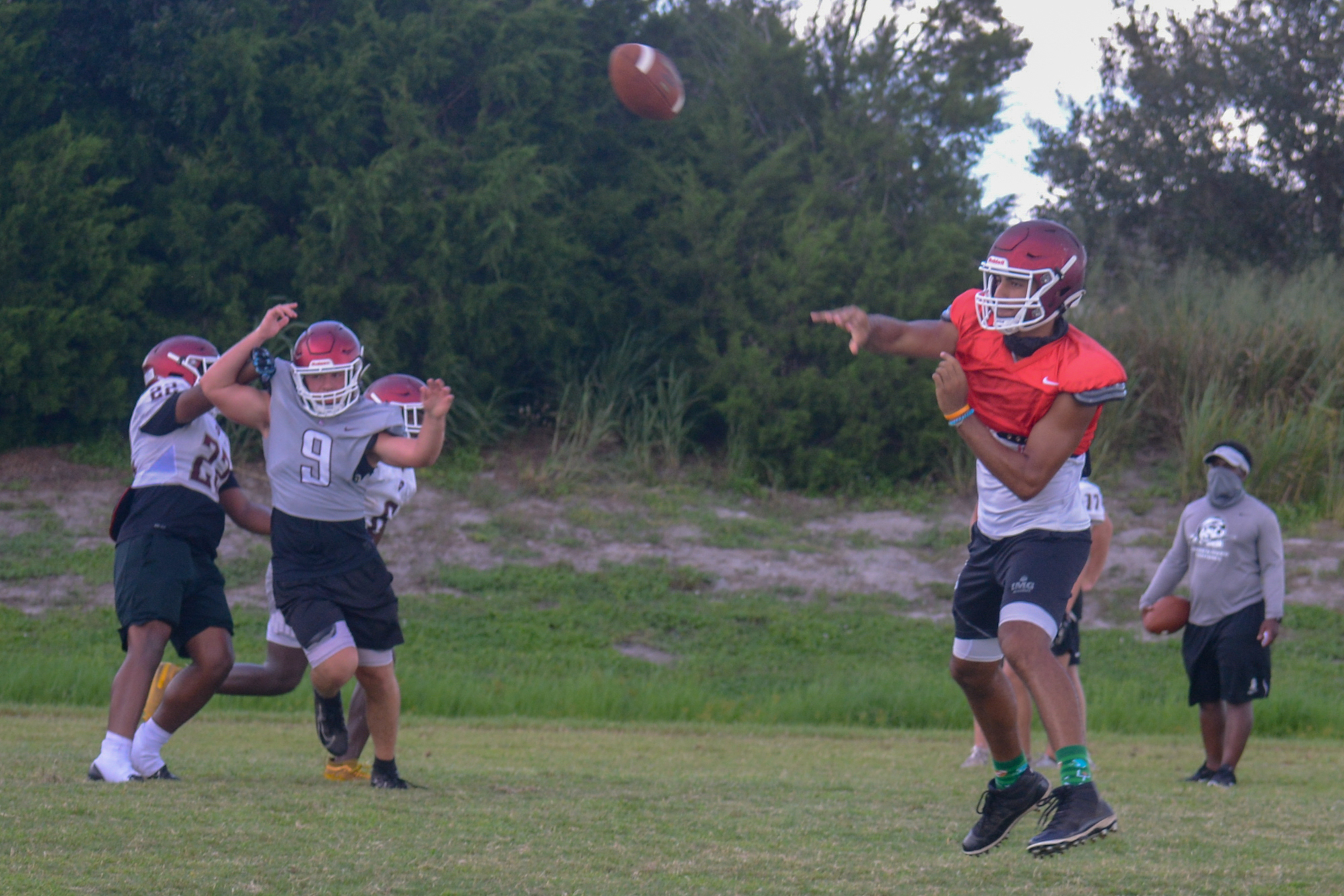 Braden River quarterback Shawqi Itraish (red jersey) floats a pass to the left side of the field during practice.