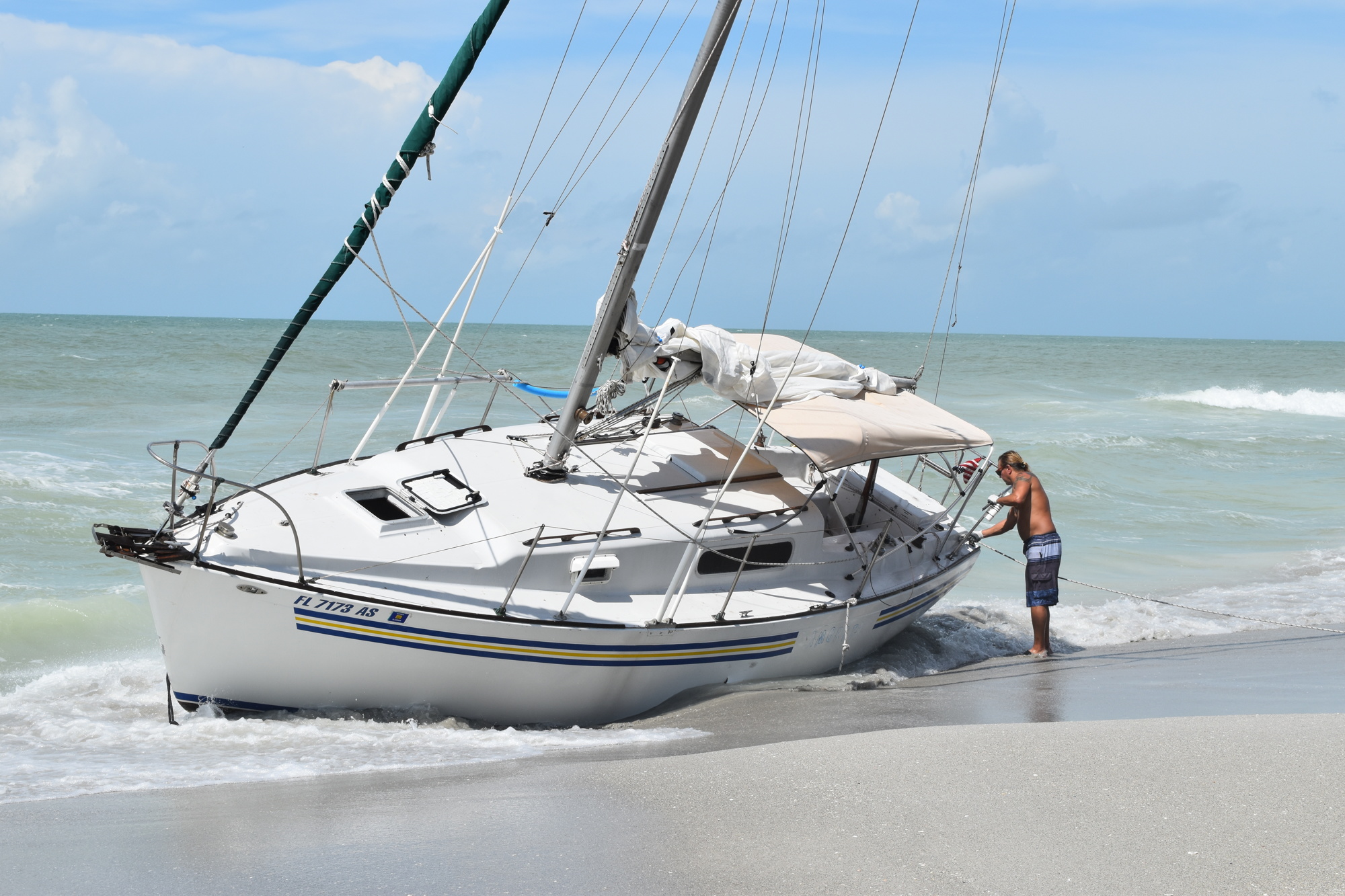 Mark Sternal examines his sailboat washed ashore near 4239 Gulf of Mexico Drive in Longboat Key, Florida.