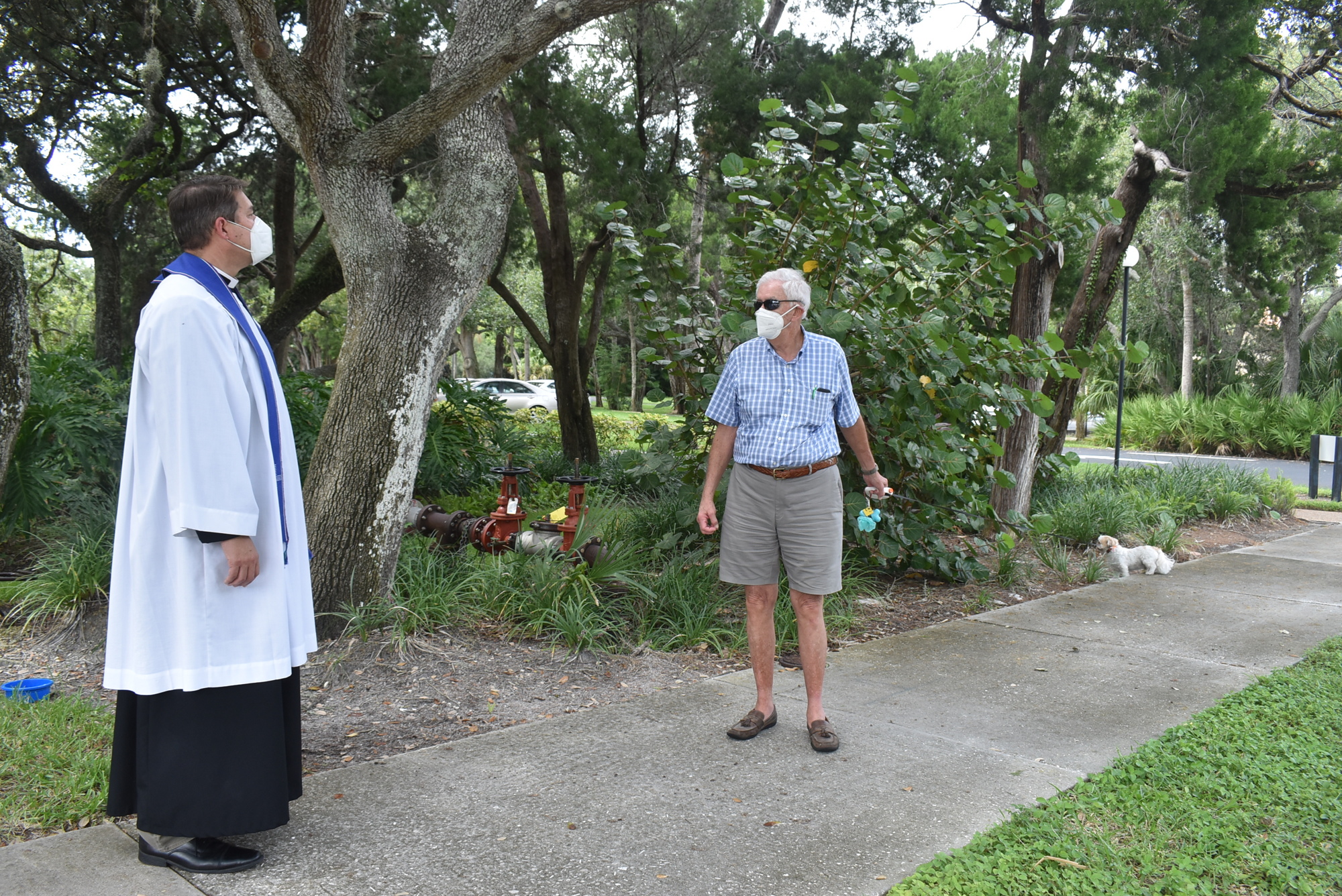 Father Dave Marshall chats with Ed Ortiz as Buddy explores the grounds.