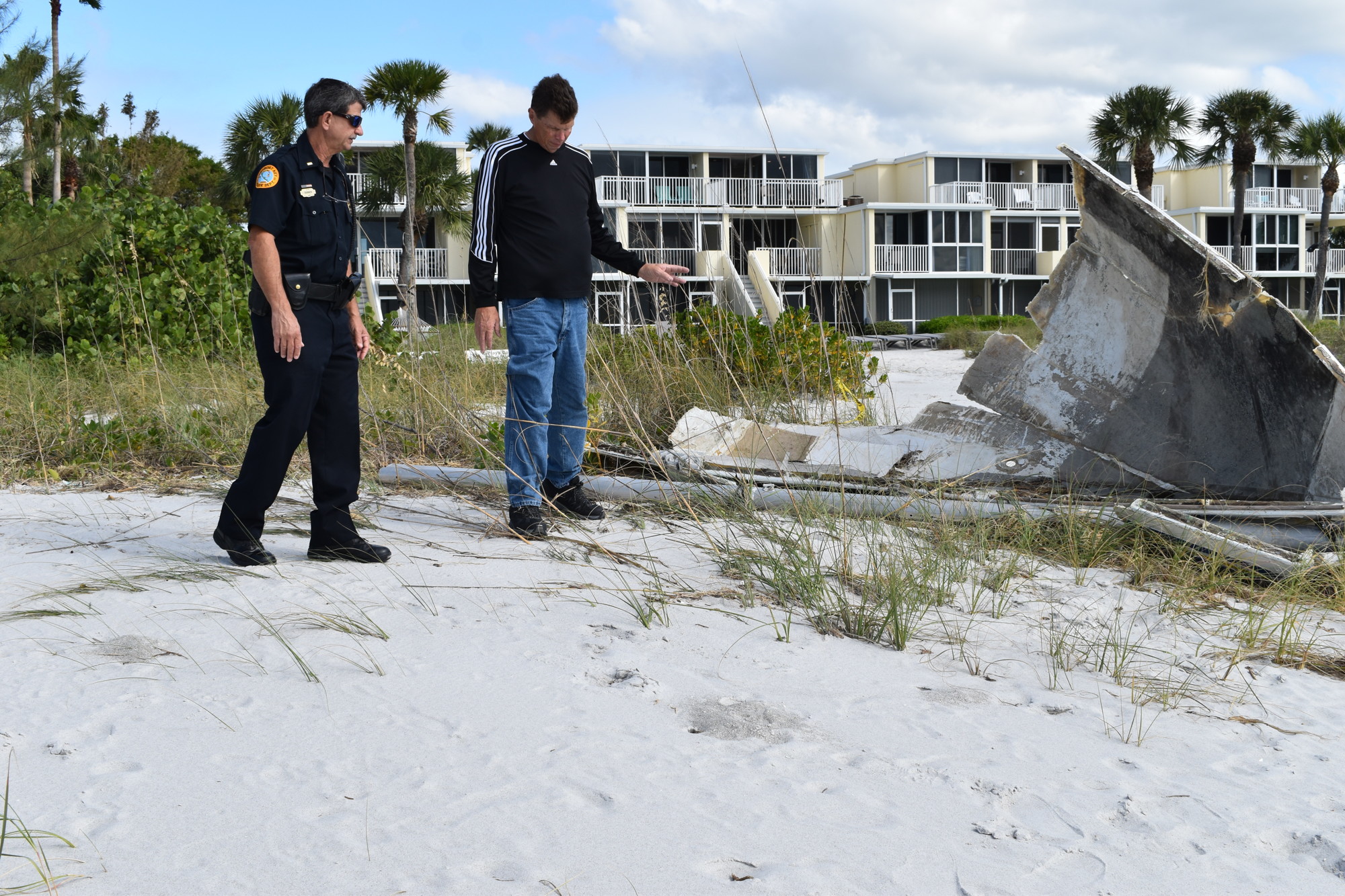 Longboat Key police officer Chris Skinner and Sea Tow owner Duke Overstreet examine the sailboat debris on Thursday afternoon in front of La Playa Rental Condominiums at 4425 Gulf of Mexico Drive.