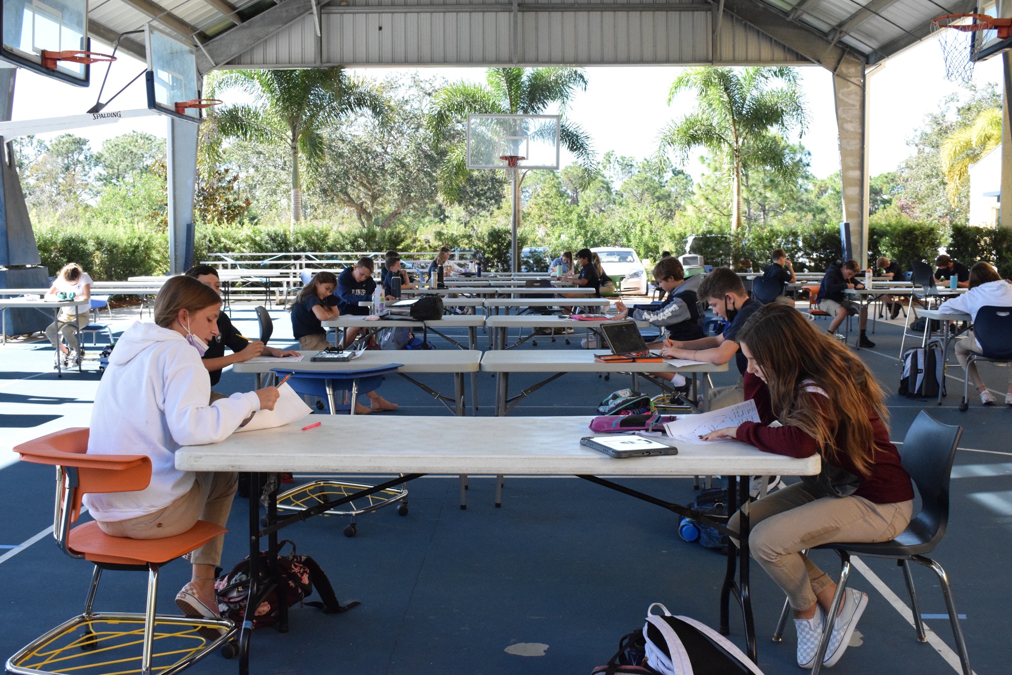 A geography class is purposefully scheduled to be held on the basketball courts to take advantage of the outdoor space.