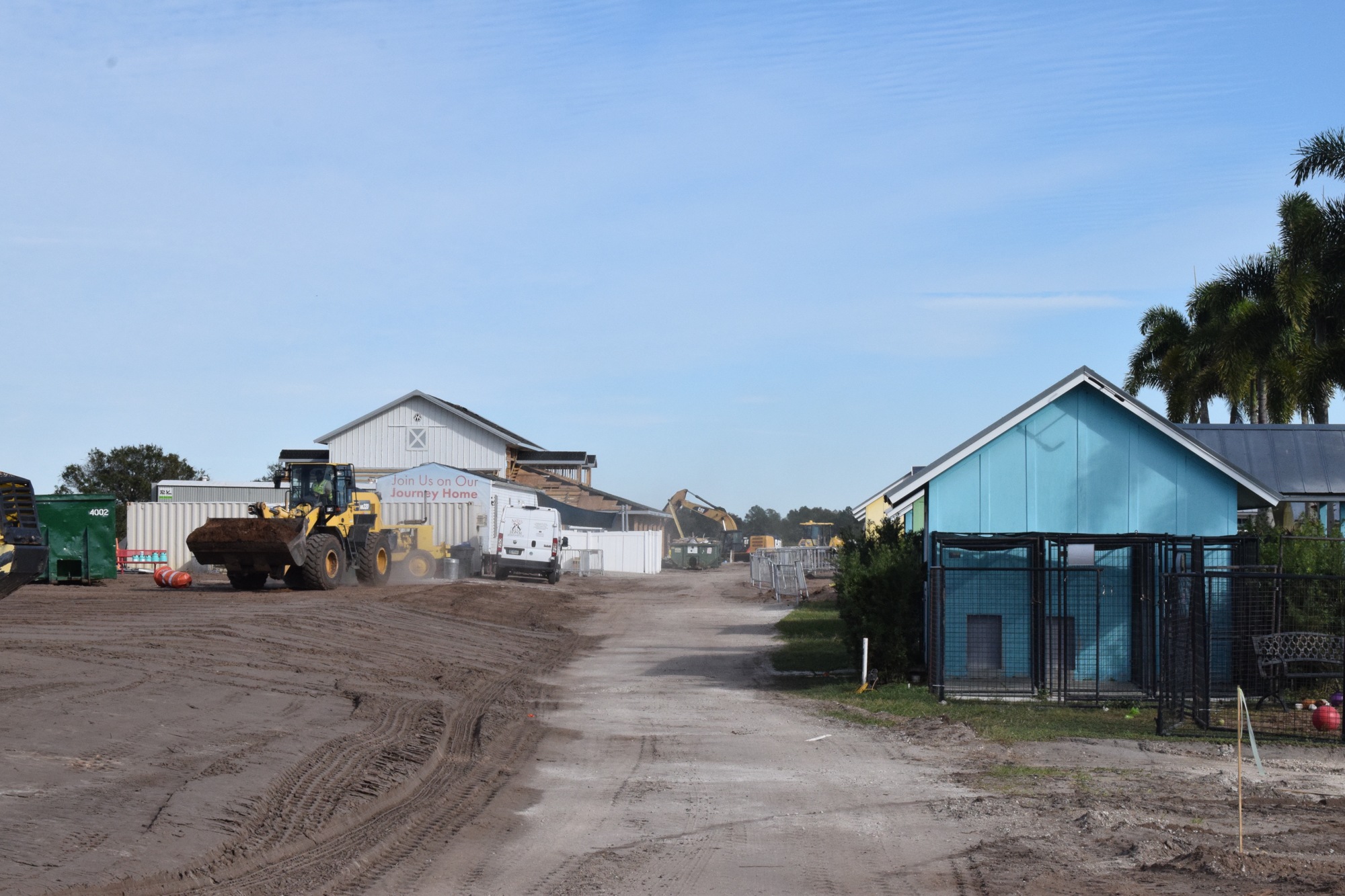 A front loader makes its way to the front of the property with dirt from the lake.