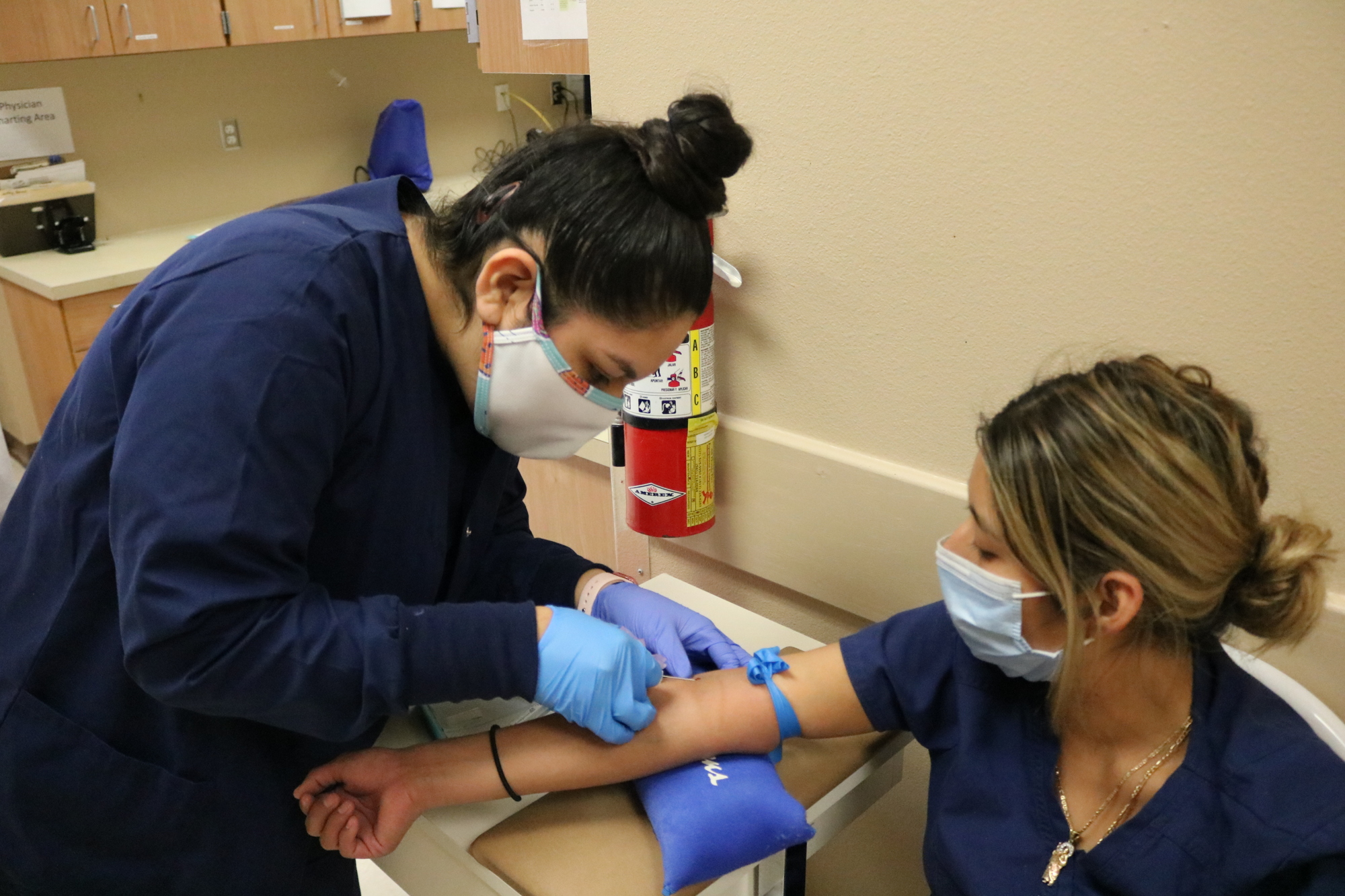 Jackie Pizano, a Phlebotomy student, learns how to draw blood from her classmate, Anahi Vasquez. Courtesy photo.