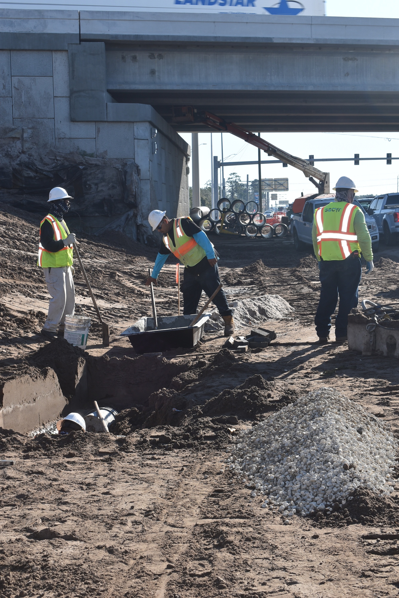 John Woodbury, Isai Rodriguez (in hole), Jose Gonzalez and Primo Gaines, who all work for construction company Sacyr, work on stormwater drainage between the I-75 bridges over State Road 70.