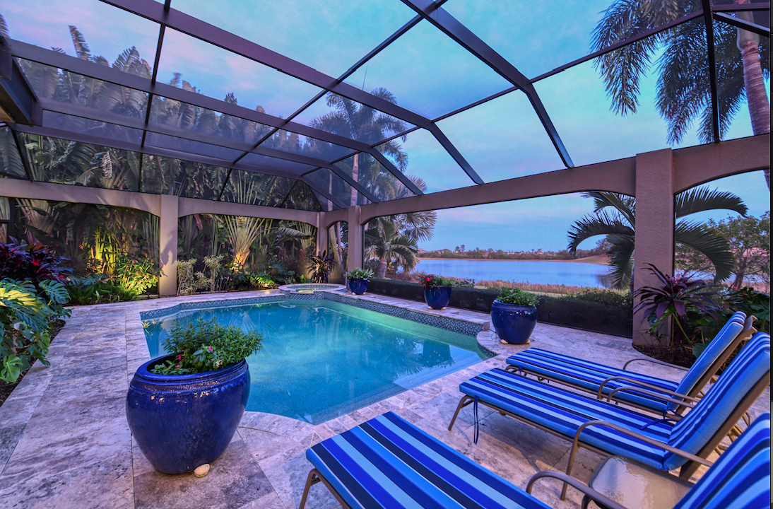 A water view framed by tropical palms highlights a lavish home in The Lake Club.