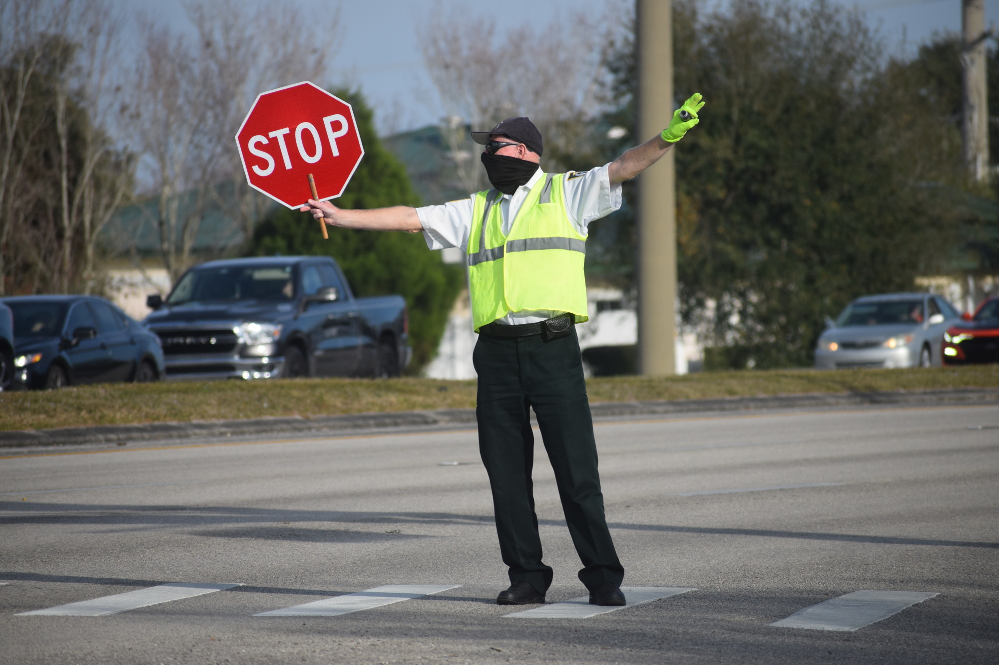 Thomas Widman, a crossing guard, holds up a stop sign to stop traffic as students make their way across State Road 70 after school.