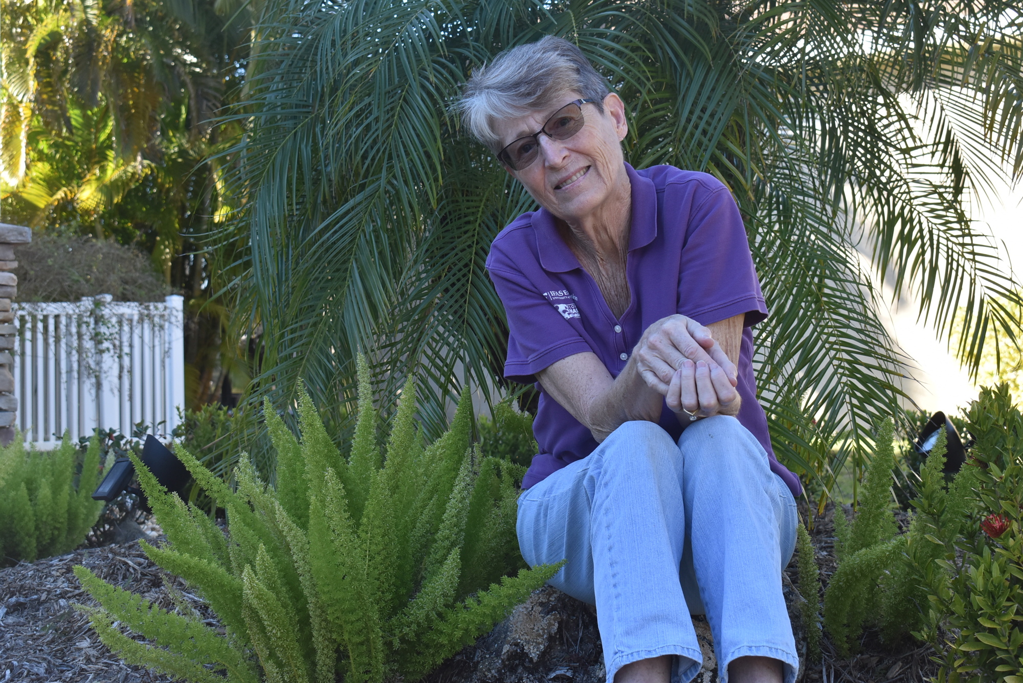 Lori Walker sits with her foxtail ferns and pygmy date palm in the garden in front of her house. Walker believes her gardens help her stay in touch with nature.