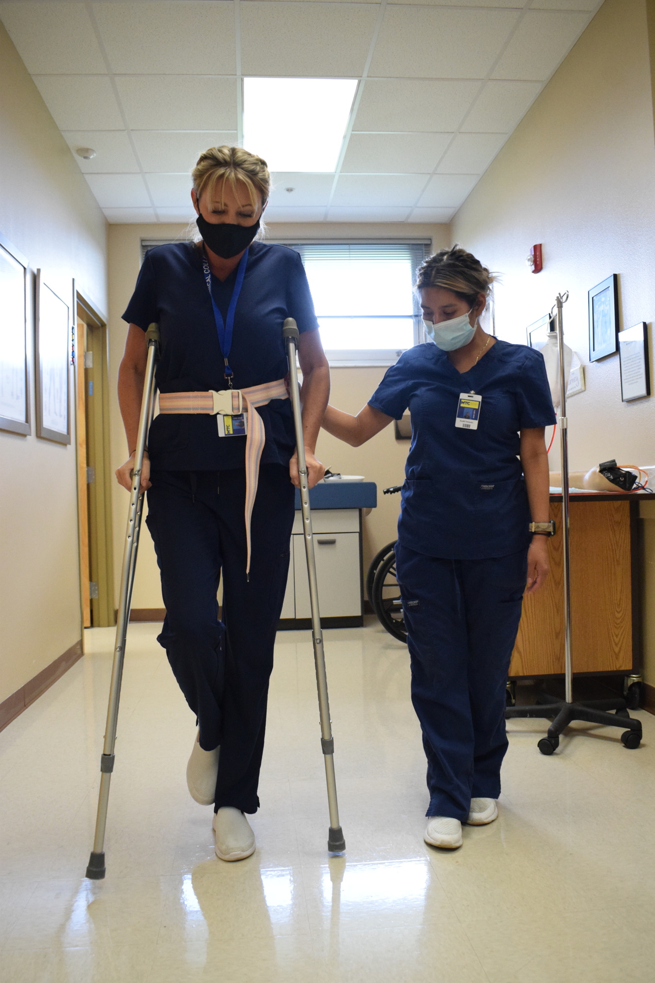 Valerie Temple, a hybrid Medical Assisting student, learns how to use crutches alongside Anahi Vasquez.