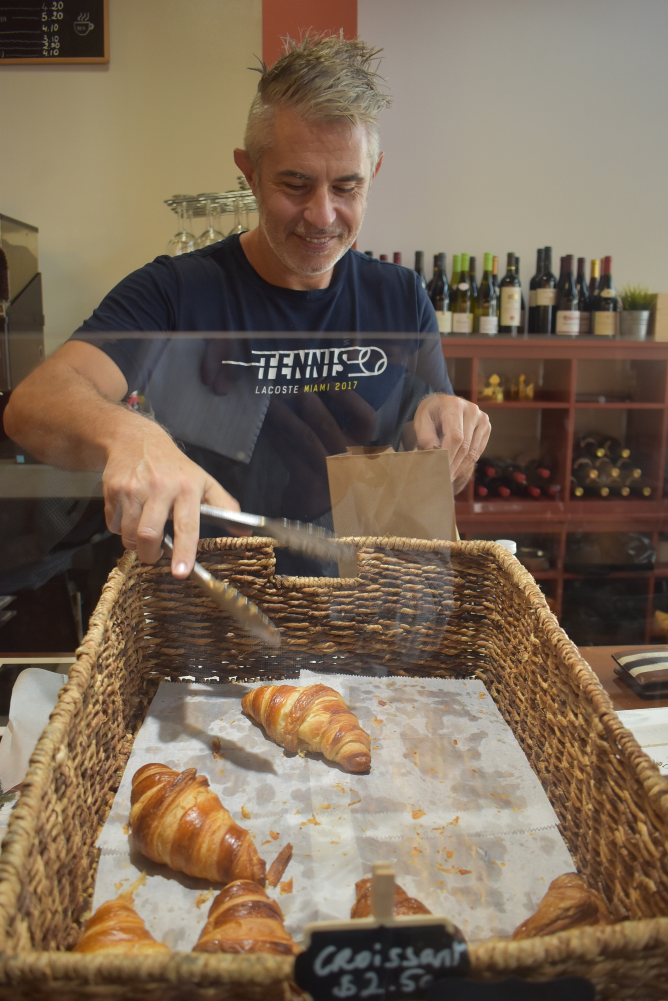 Jean Dandonneau selects a croissant to put in a to-go bag. Since becoming Mademoiselle Paris, the Dandonneaus have added new items to the menu, such as maple bacon croissants.
