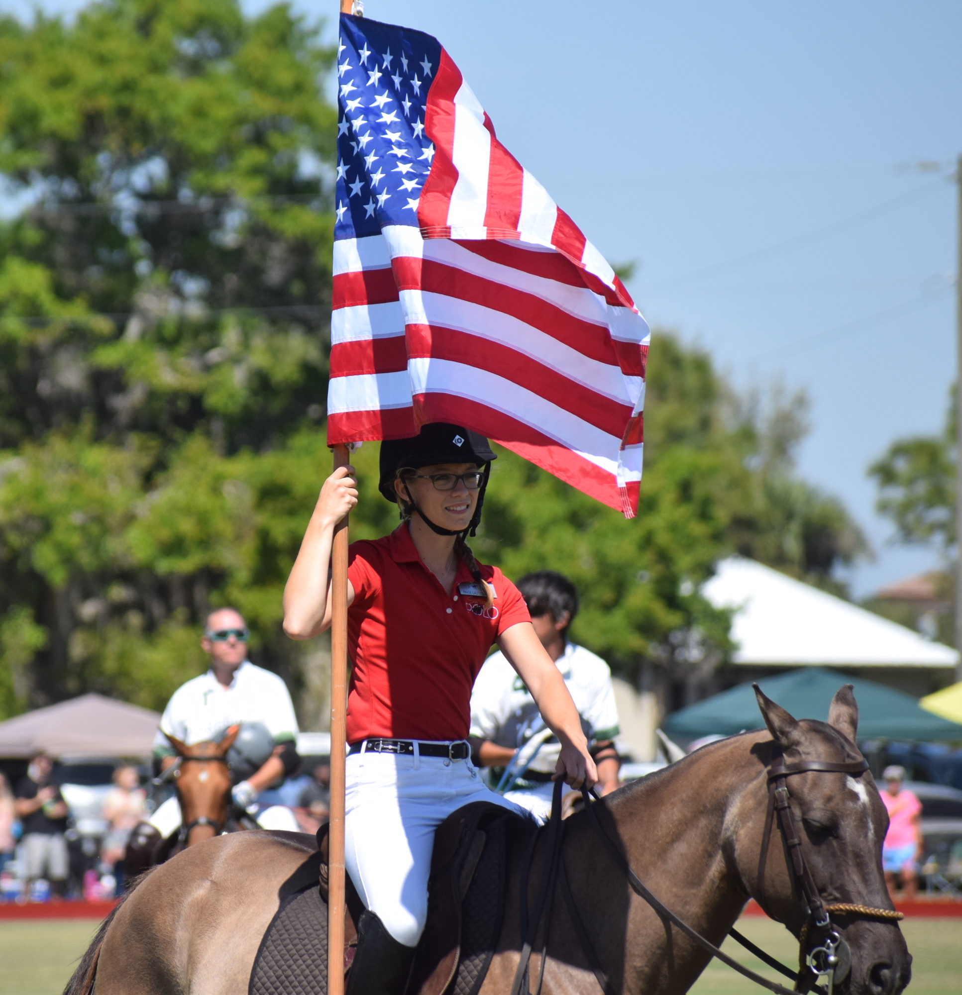 Paige Lautzenheiser, the director of operations for the Sarasota Polo Club, presents the colors.