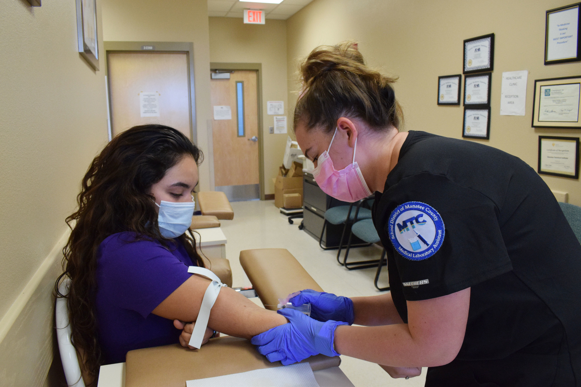 Lakewood Ranch High School senior Suzanne Aguirre helps Alexis McClintock, a Braden River High School senior, practice drawing blood. They are in Manatee Technical College's dual enrollment program for Medical Laboratory Assisting
