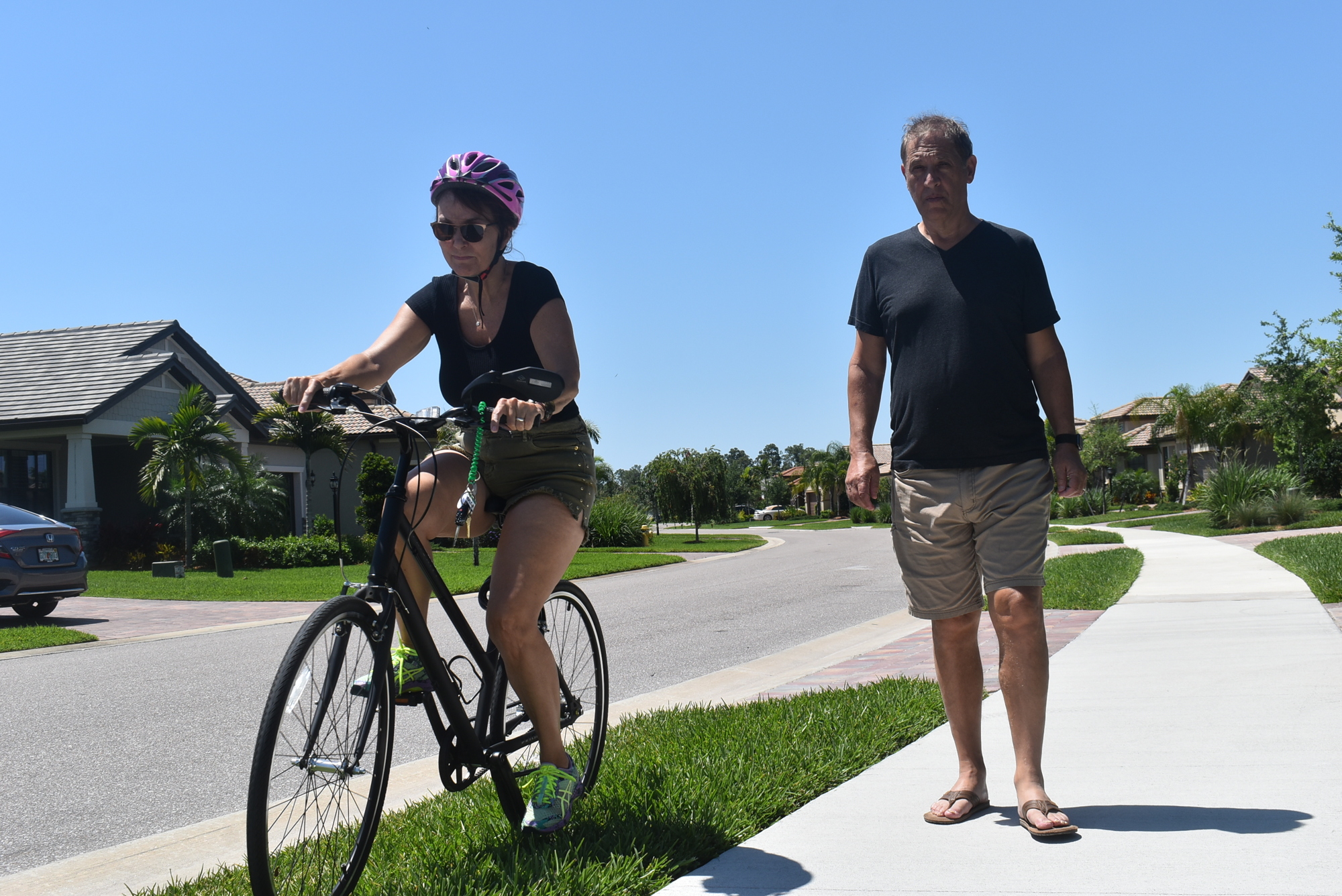 Janet Savar rides in the grass around Gene Savar as he walks through Del Webb. Janet Savar said she doesn't mind riding in the grass to pass pedestrians if they don't hear her. Other cyclists say it is inconvenient.