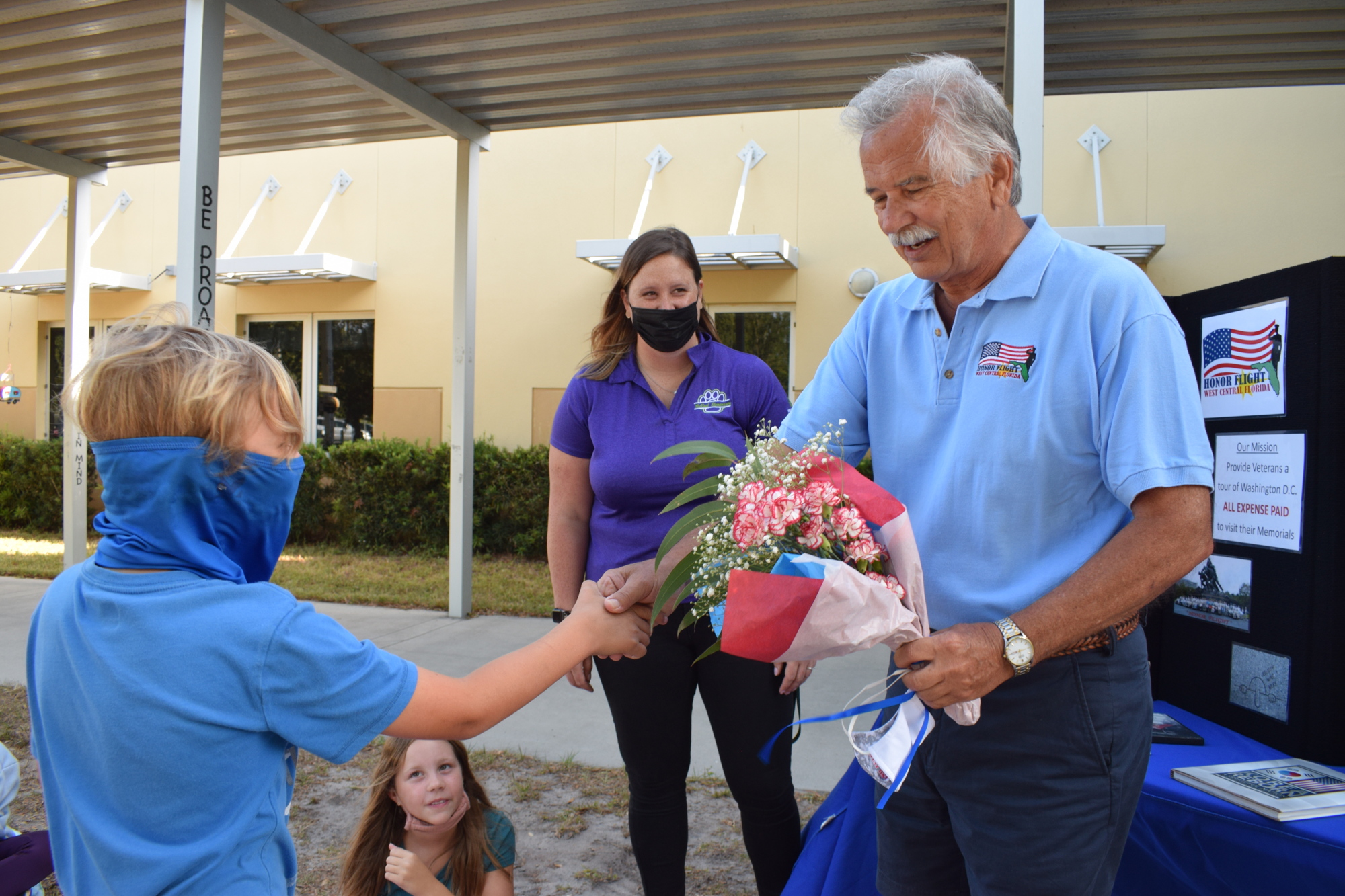 Fifth grader Colt Smith gives Gary Gilchrist, a director of Honor Flight of West Central Florida, a bouquet of flowers.