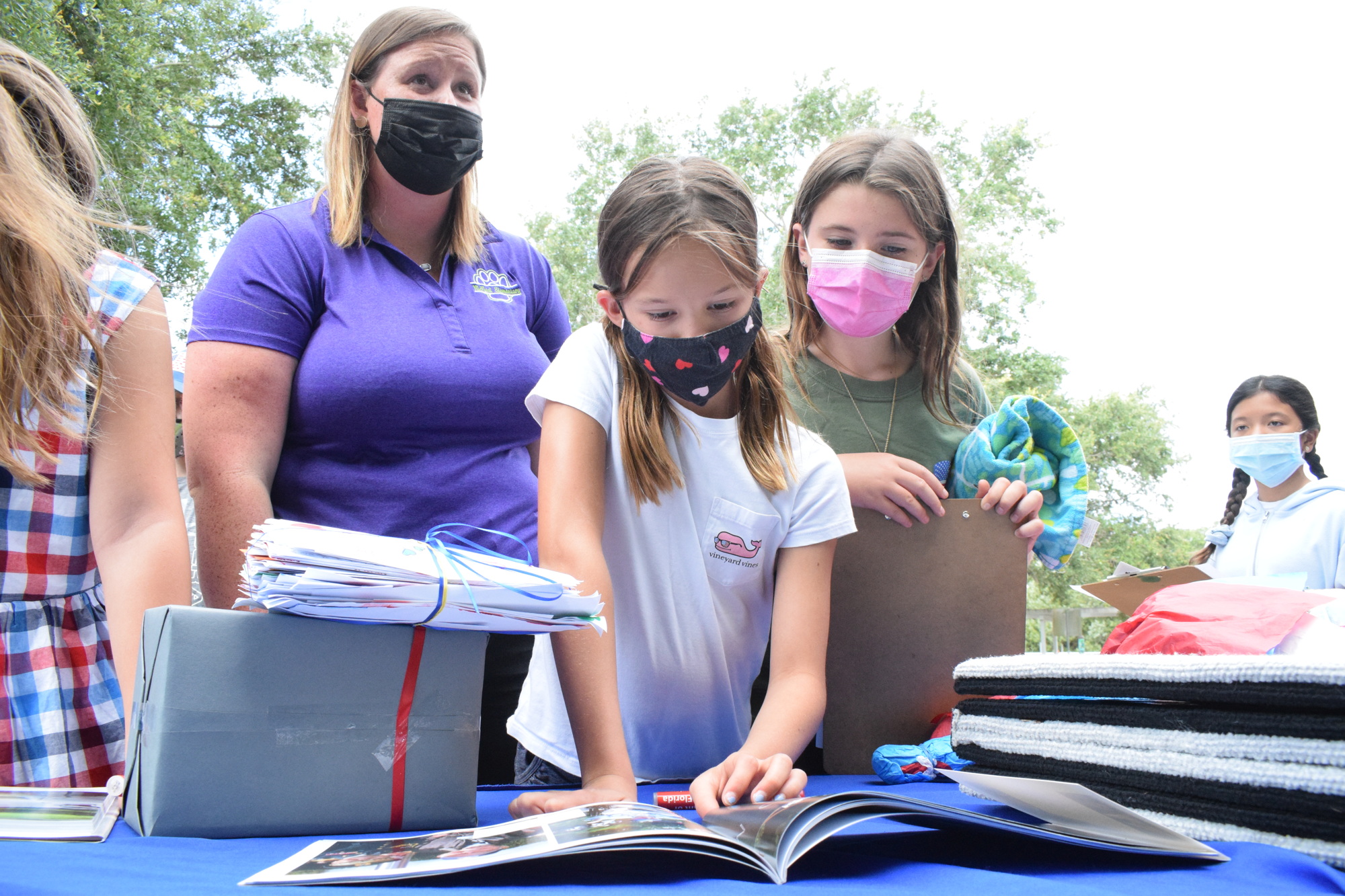 Olivia Swartling, a fifth grade teacher, and her students, Morgan Elliott and Sophia Jensen, look at a book showcasing the mission of Honor Flight of West Central Florida.