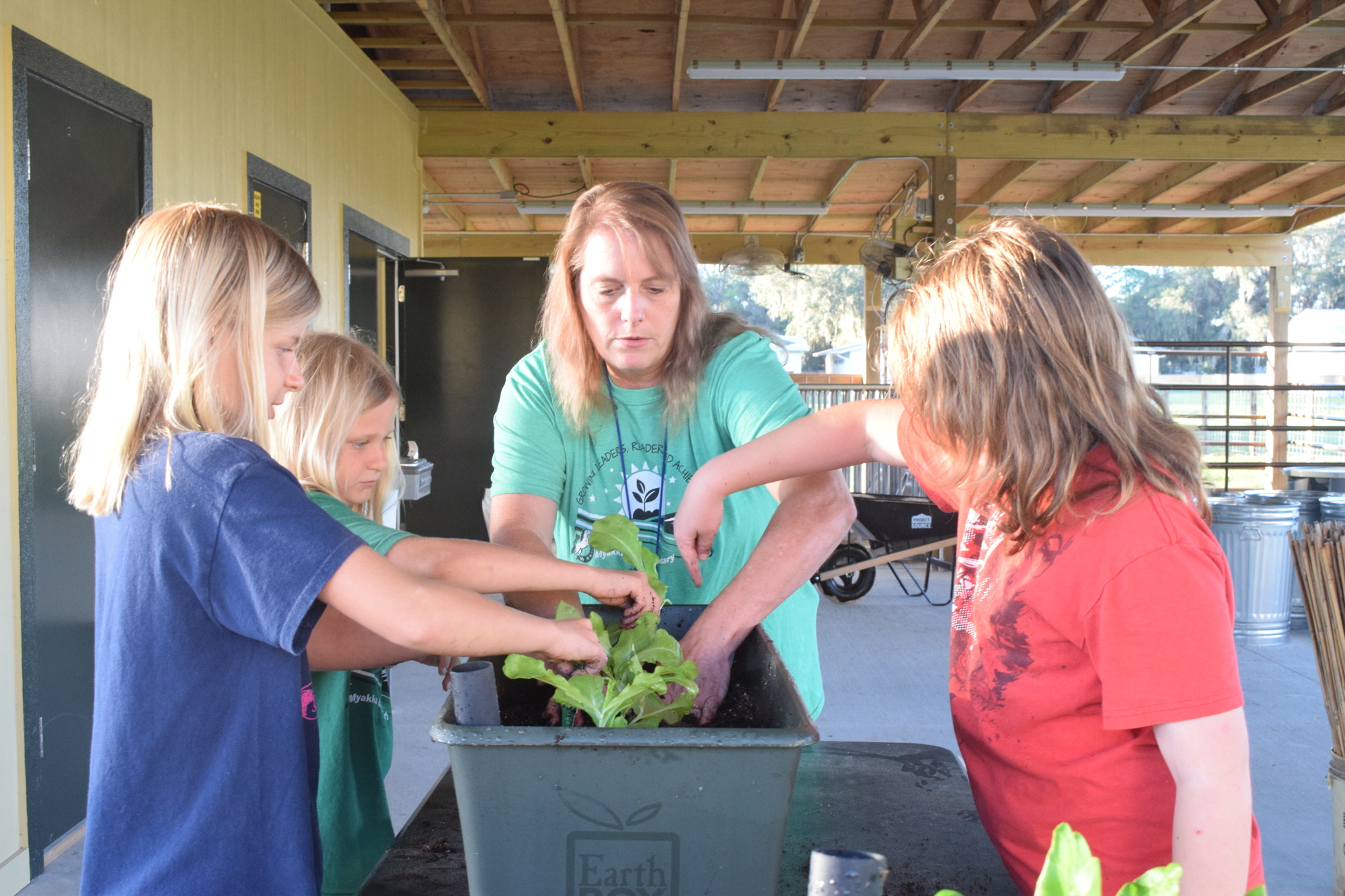Fifth grader Grace Lockhart, fourth grader Layla Lockhart, agriculture science teacher Temple Bunyak and fifth grader Elijah Blackman work on planting lettuce in an EarthBox.