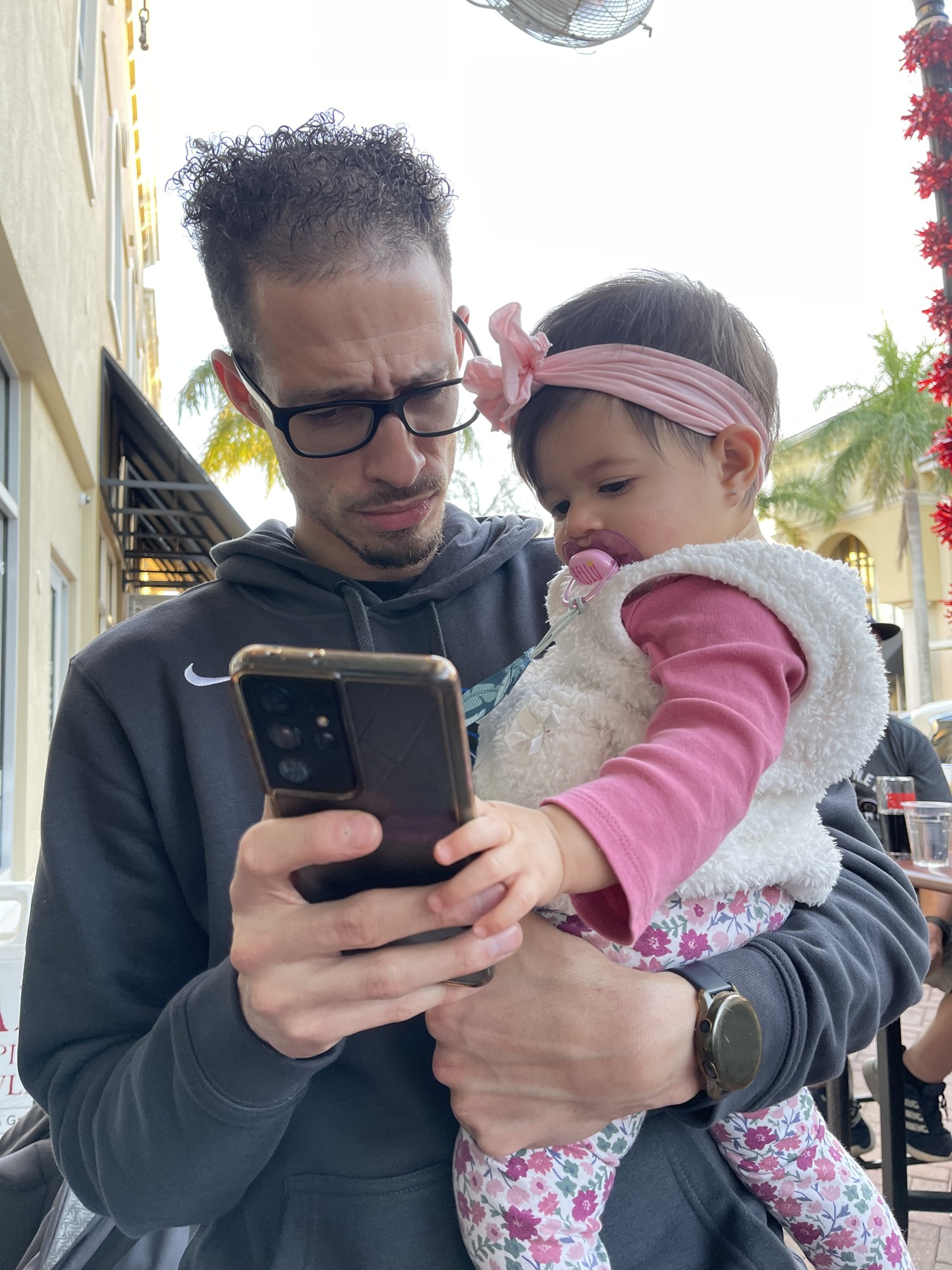 Louis Morales struggles to get a YouTube video loaded for his daughter Zara to watch while they enjoy Main Street Lakewood Ranch. Morales said he's been dealing with inconsistent service from T-Mobile for five years.