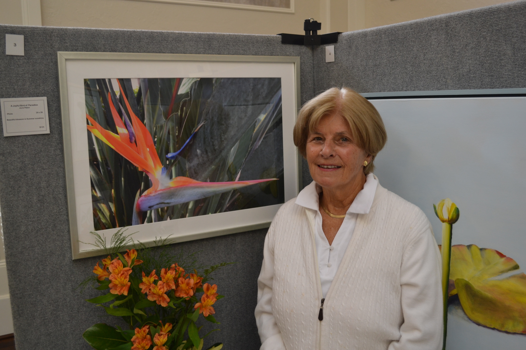 June Paton stands beside her favorite photo, which depicts a bird of paradise.