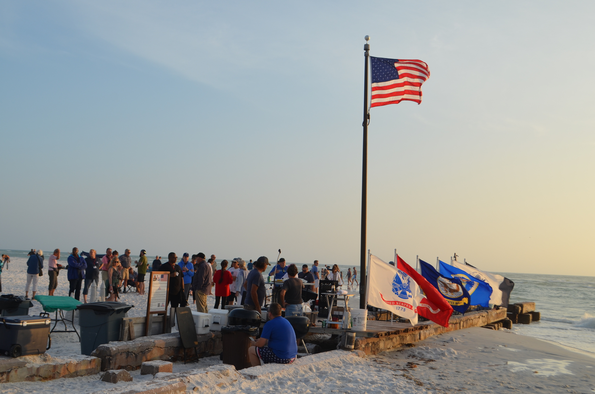 An American flag waves next to military flags on Siesta Key Beach.