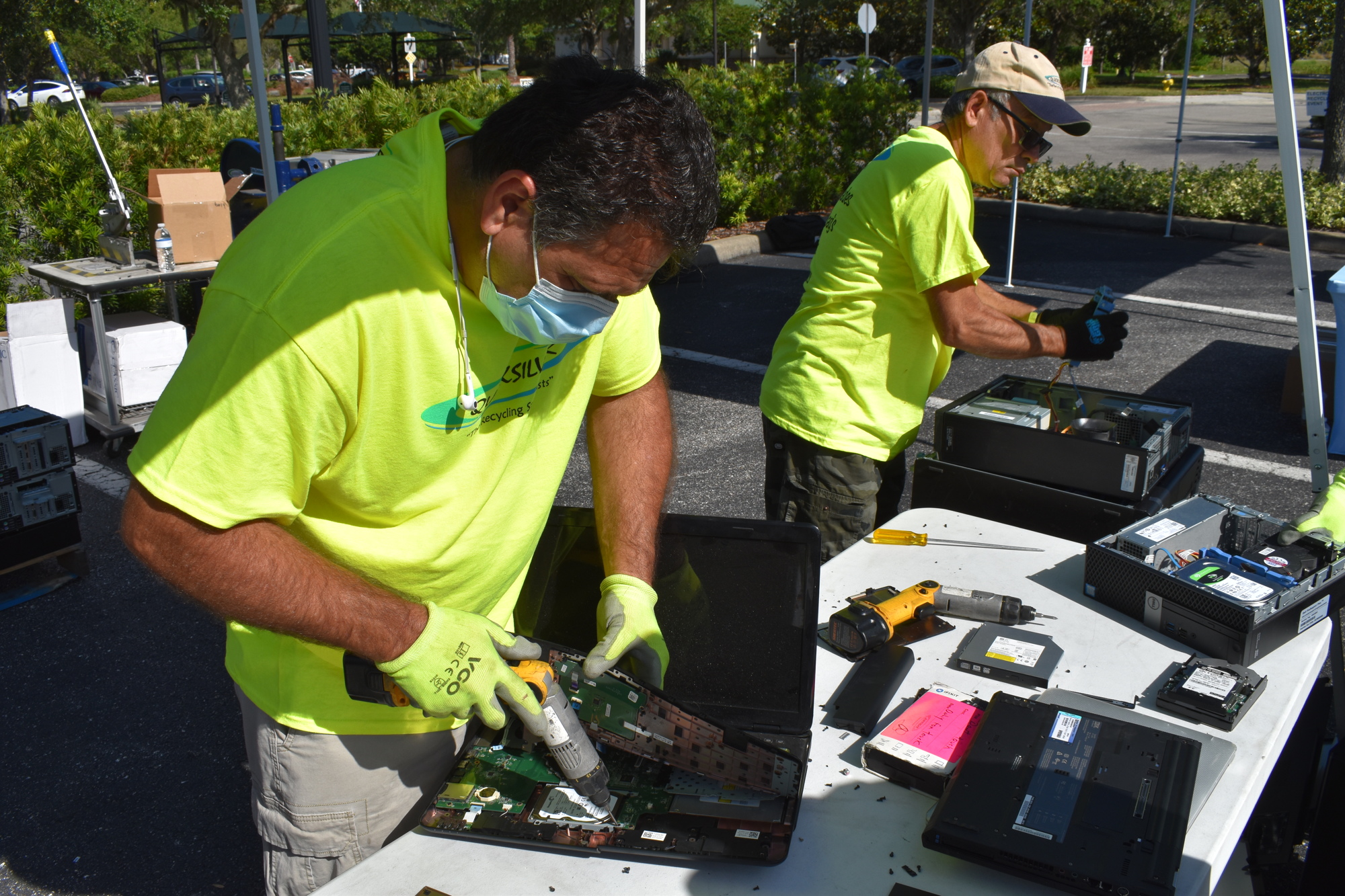 Ariel Villafana and Lazaro Sanchez break apart computers to remove the hard drives.