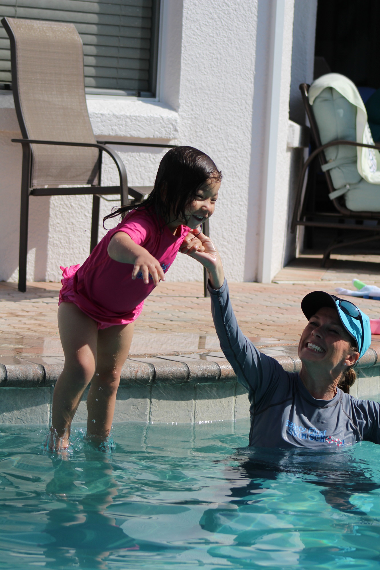 Two-year-old Penelope practices feet first dives with Tanya Jablon's assistance.