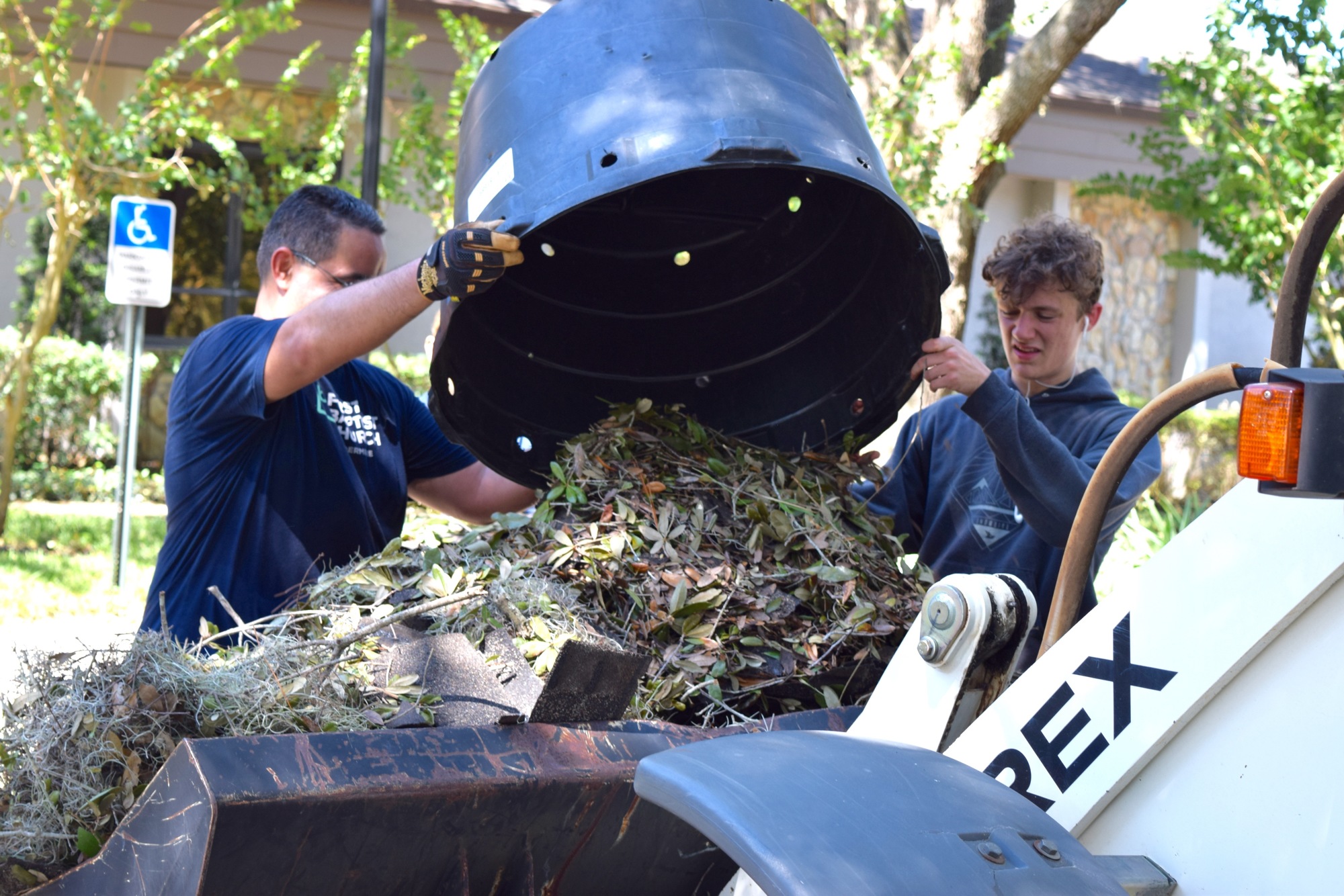 Volunteers Nelson Bonet and Zach Taggert worked together to dump a load of debris onto a machine.