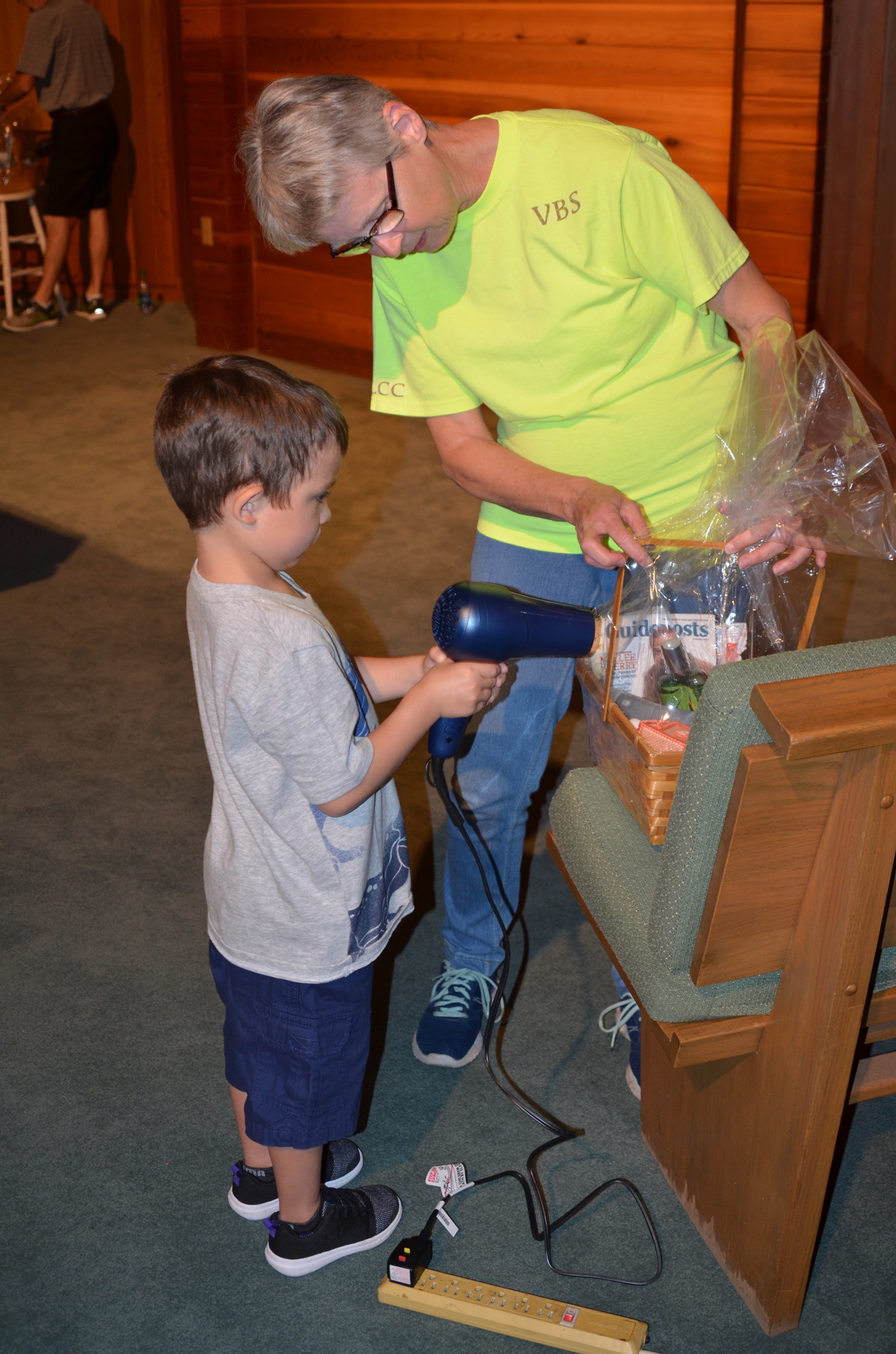 Landon Bliven assists Diane Gardner in shrinking the cellophane on a Mother’s Day basket. Landon’s mother received a similar basket last May when they were in the hospital for Landon’s medical treatment for leukemia.