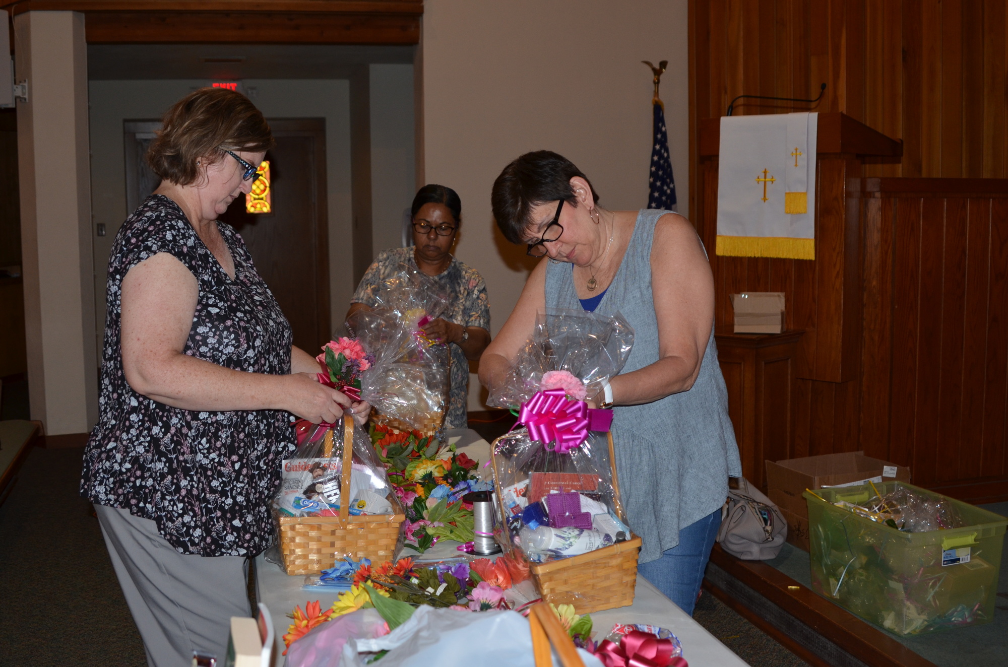 Tammi Warchocki, left, Roseanna Koppinger and Suzy Smith decorate the baskets with ribbons and bows.