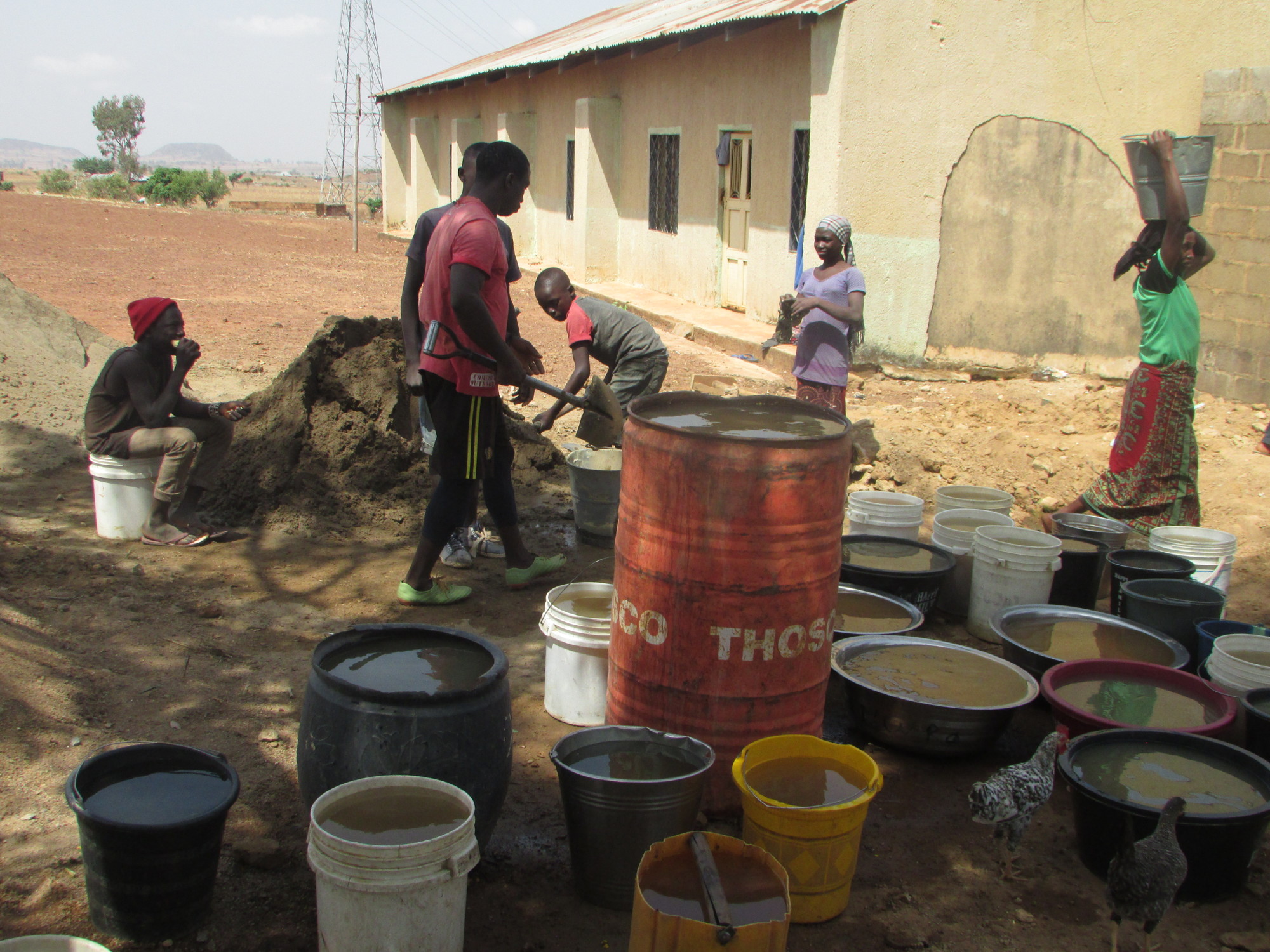 Women fetch water so the men can mix concrete for the house construction.