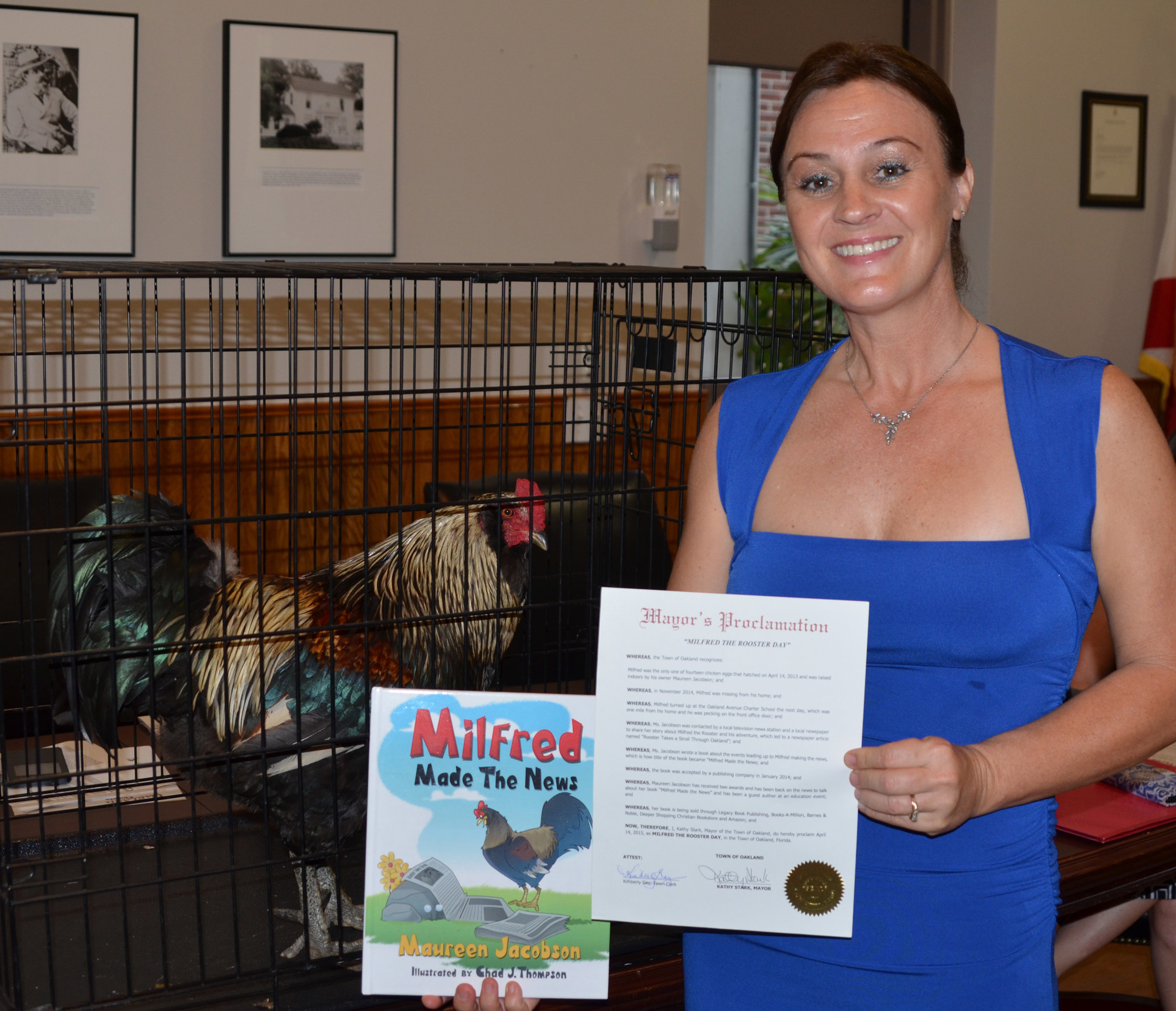 Milfred the rooster examines his book and mayor’s proclamation, held by his owner, Maureen Jacobson, in April 2015.