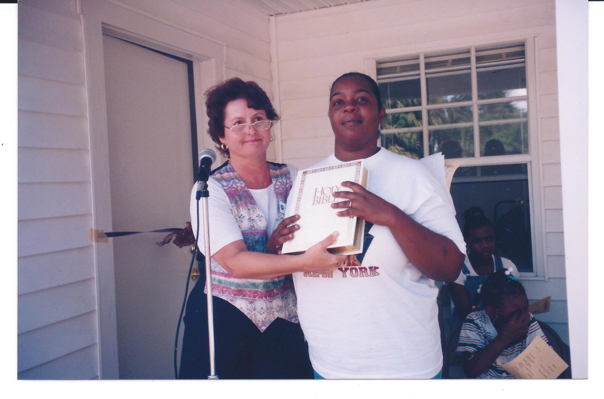 Jackie Reynolds received a Bible from Anne Walding at the ribbon-cutting for her new Habitat home in 1997.