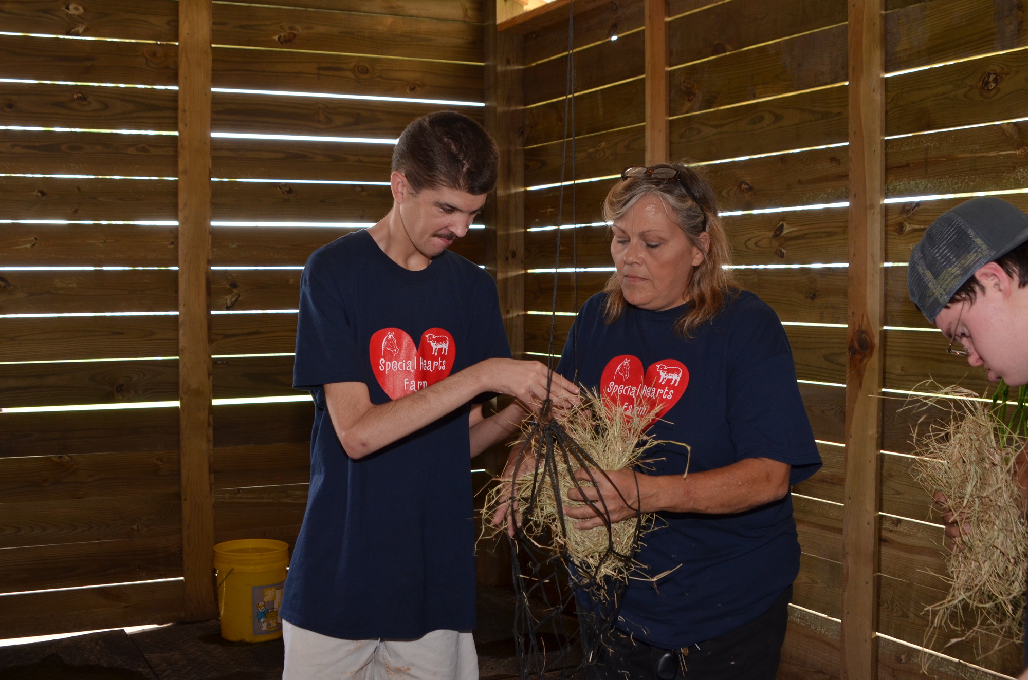 Evan Pryor helps staff member Sherry Easley with the hay.