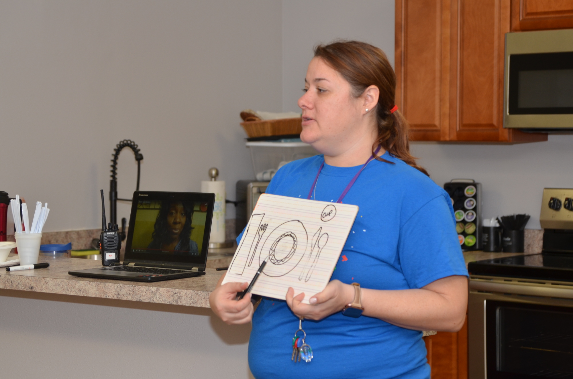 Staff member Kelly Calenback shows students how to set a table.