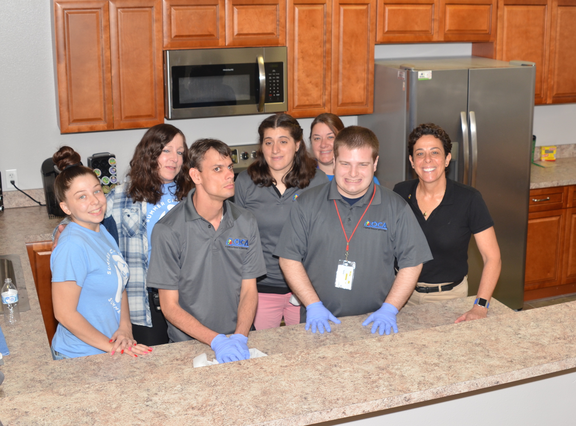 Staff members Angela Earl and Lisa Earl, Brandon Barley, Bianca Longhi, staff member Kelly Calenback, Zach Carter and director Silvia Haas work on kitchen-cleaning skills.