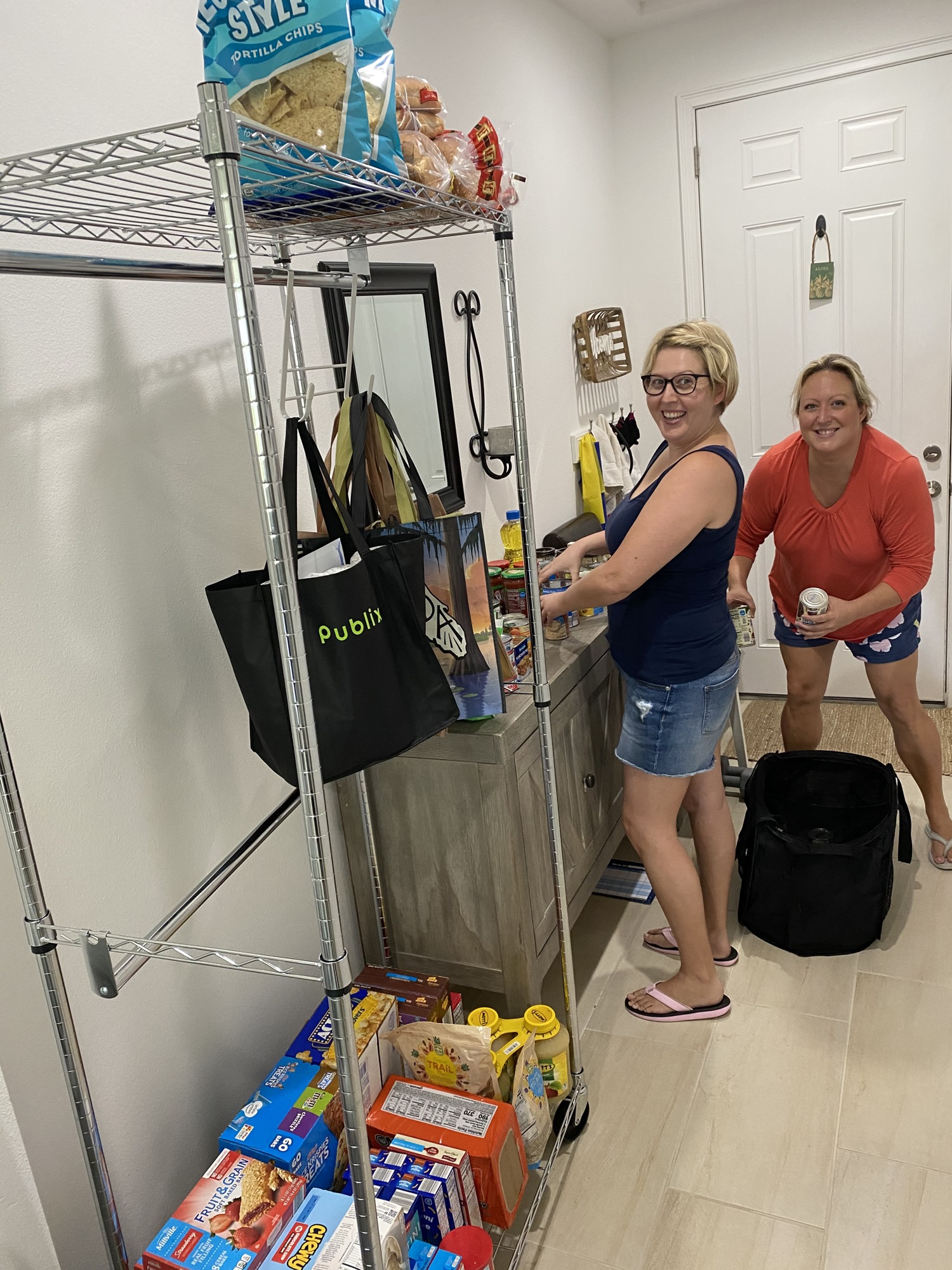 The “giving pantry” has been set up in the kitchen hallway. Laurie Otto, left, and Christie Otto, packed up for a delivery.