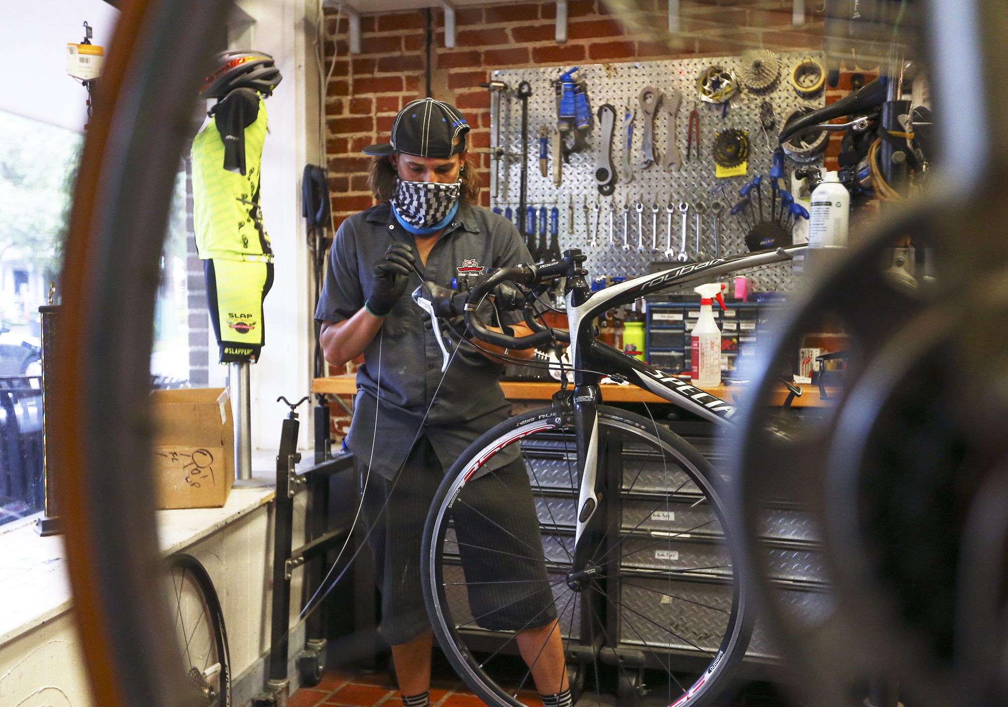 Wess Irons works on a bike during a busy day at Winter Garden Wheel Works in downtown Winter Garden.