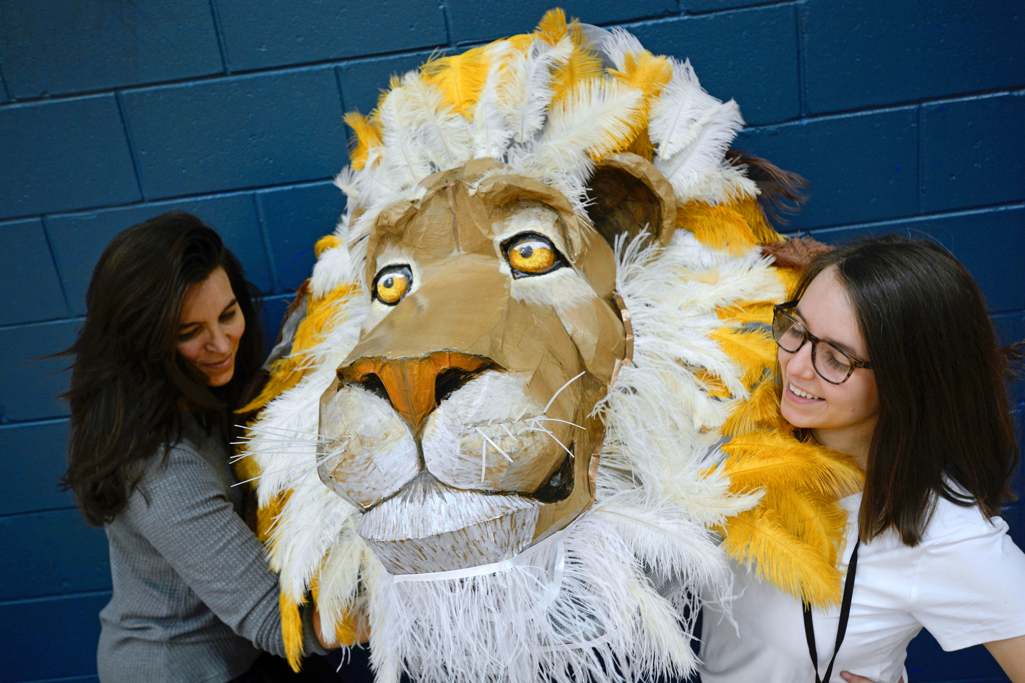 Amber Wilkins, left, vice president of Foundation Academy’s Fine Arts League, and Foundation choir and drama teacher Laurlyn Smith lift the head of the Aslan puppet, created by Wilkins, for the show.