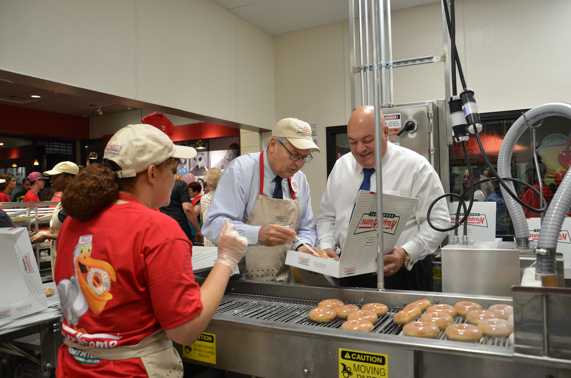 Spiro & Associates arranged for Fort Myers Mayor Randy Henderson (left) and city councilman Cecil Pendergrass to box the first dozen doughnuts during Krispy Kreme's grand opening. Courtesy Spiro & Associates