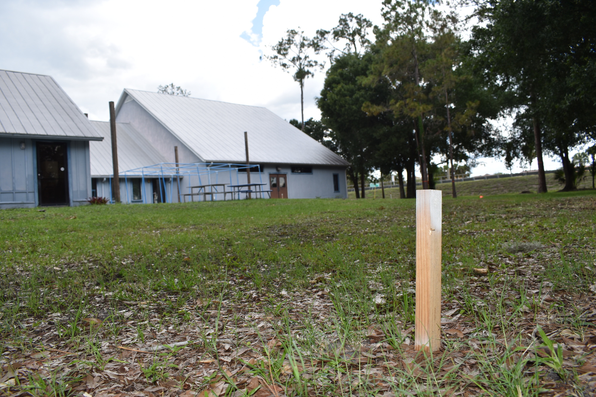 A wooden stake stands in the ground, marking a corner of the space the new events center will occupy.