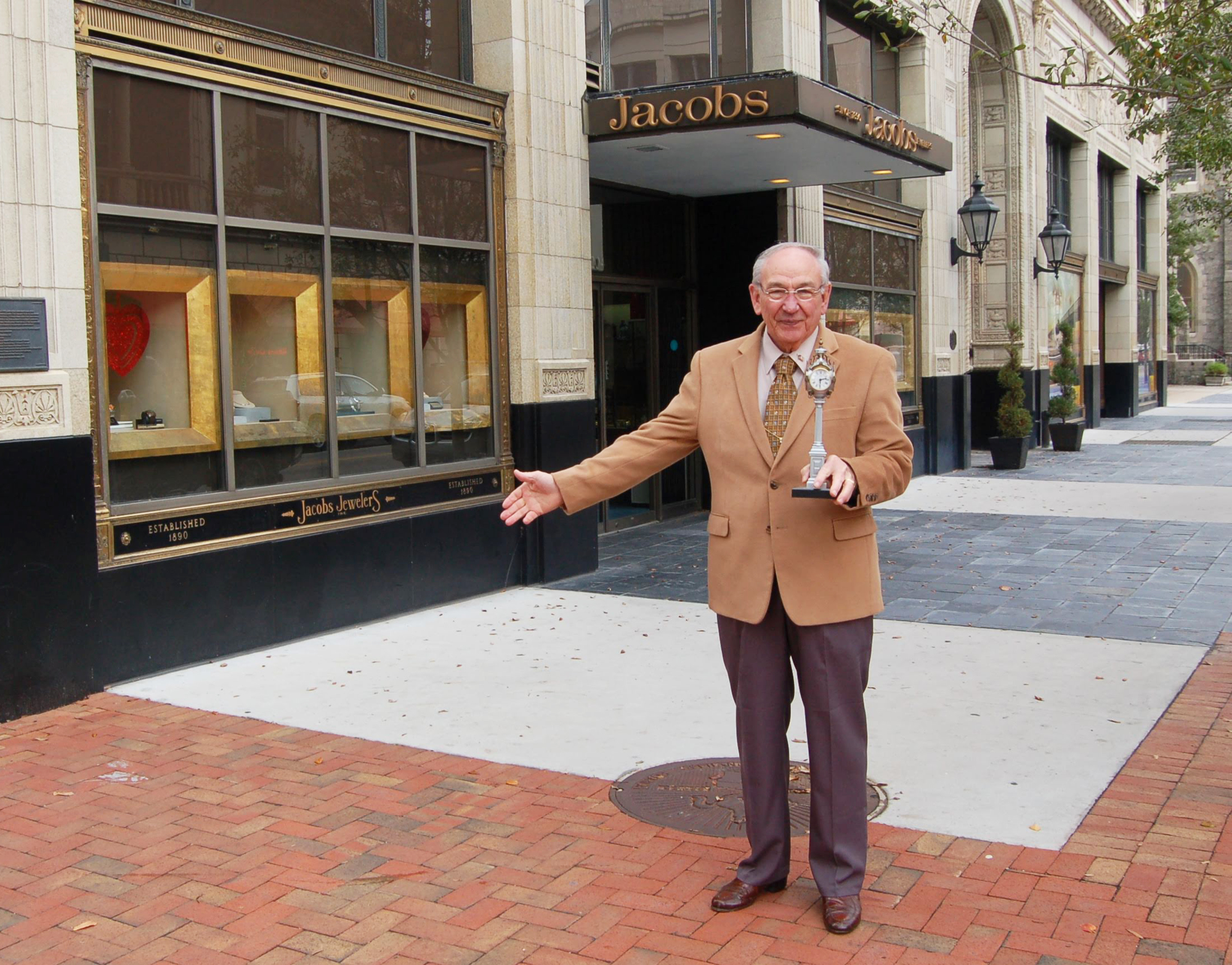 Jacobs Jewelers owner Roy Thomas stands outside his store in 2013 holding a replica of the Seth Thomas that was being refurbished.
