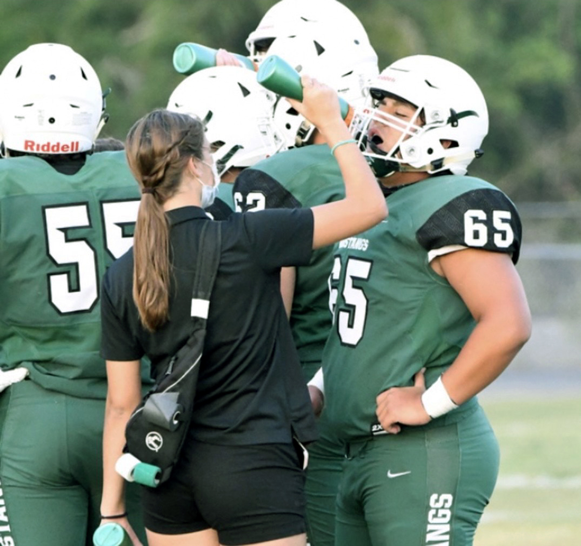 Reagan Gross, here giving water to Mustangs lineman Brian Areco, was a part of the Lakewood Ranch athletic training program for two years. (Courtesy photo)