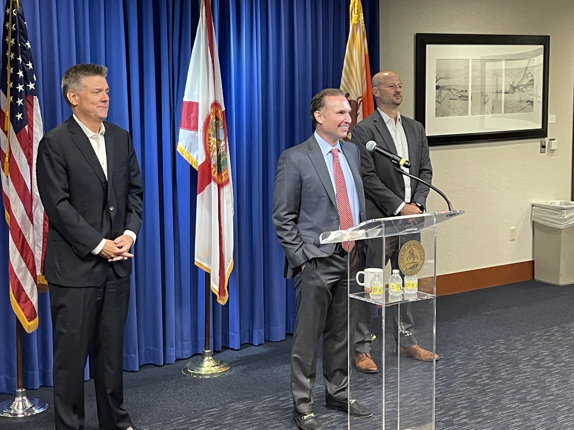 Jacksonville Mayor Lenny Curry speaks to reporters while City Chief Administrative Officer Brian Hughes, left, and city Chief Financial Officer Joey Greive watch.