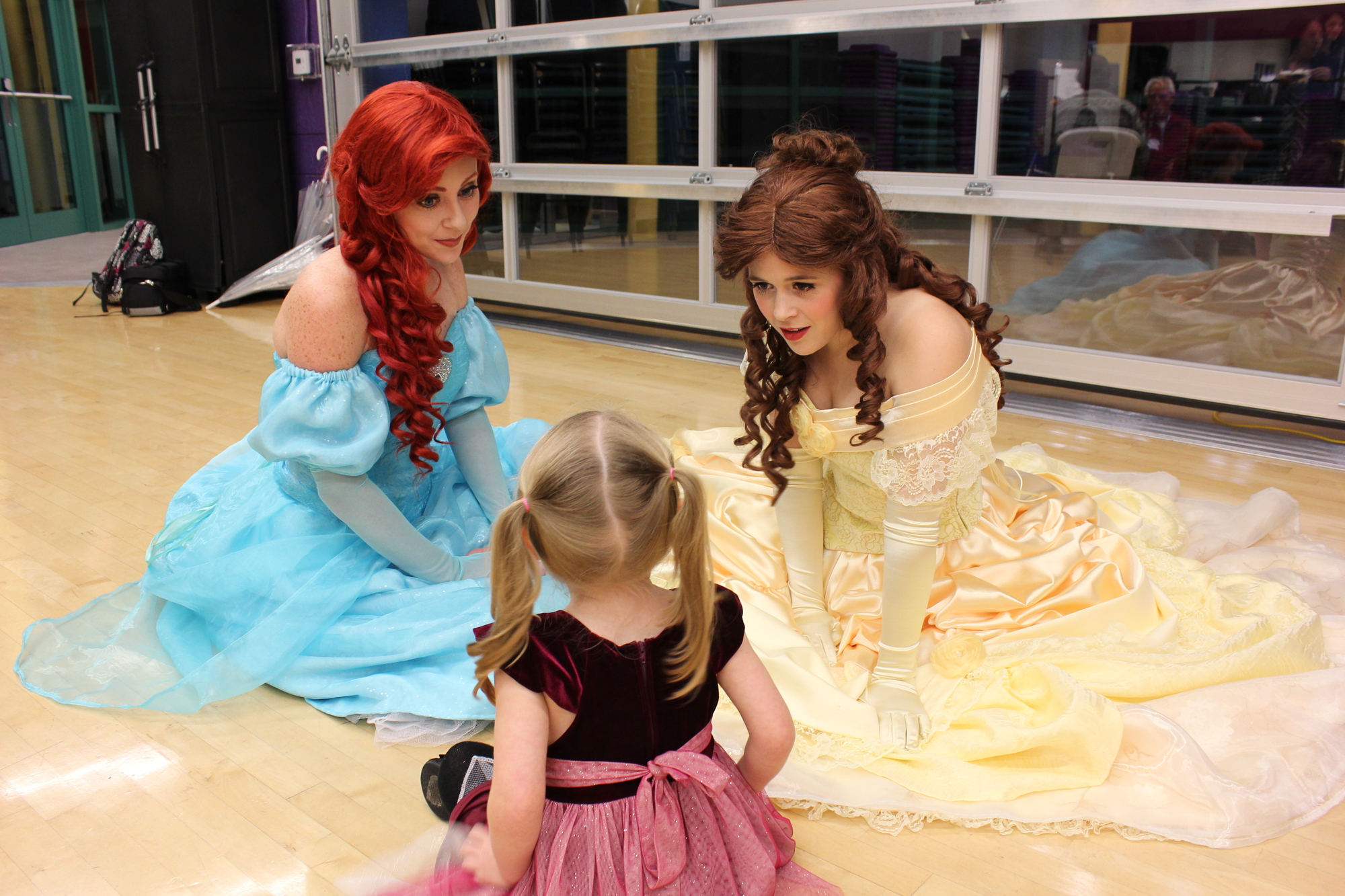 The Little Mermaid and Belle speak to a little princess. 