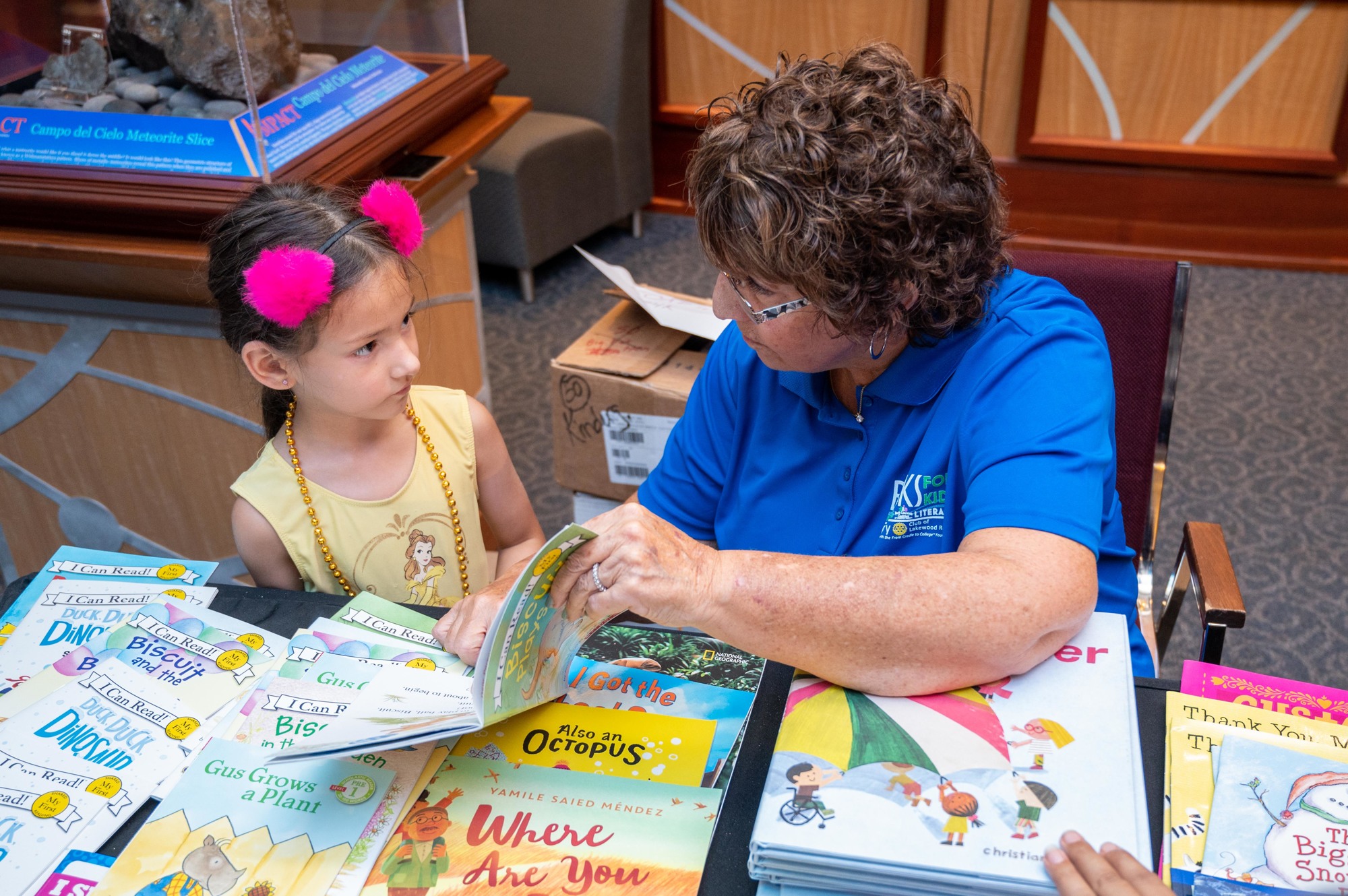 Volunteer Judy Handleman shares a book with Ariel Trego at a Books for Kids’ event in July at The Bishop Museum of Science and Nature. (Photo by Lori Sax)