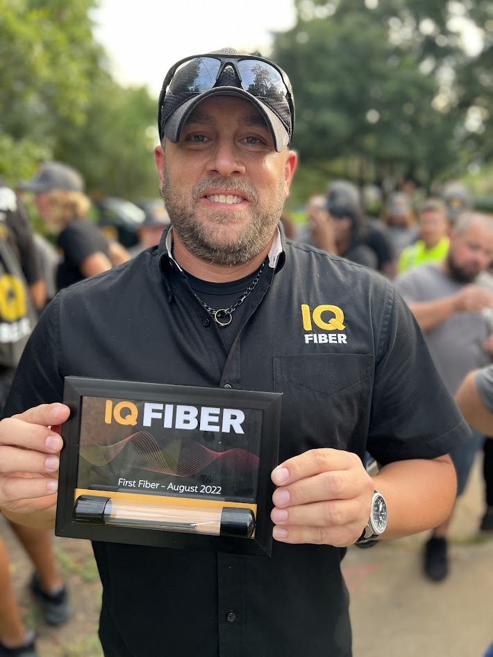 Jeremy Slater, project manager for IQ Fiber, holds a plaque given to all employees marking the first day of internet service.